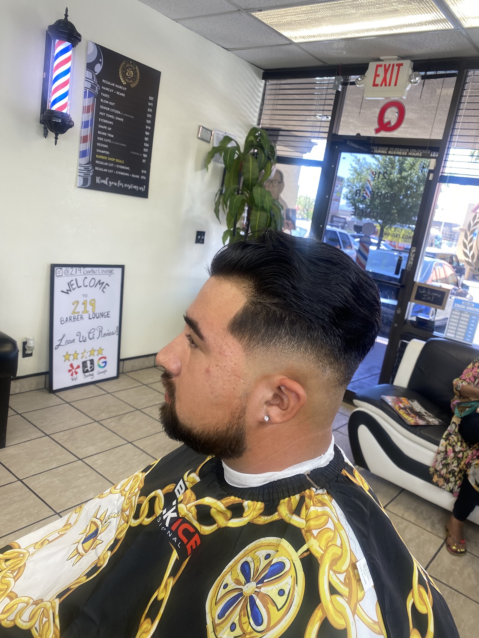 Man with fresh fade, beard trim and styled top in barber chair