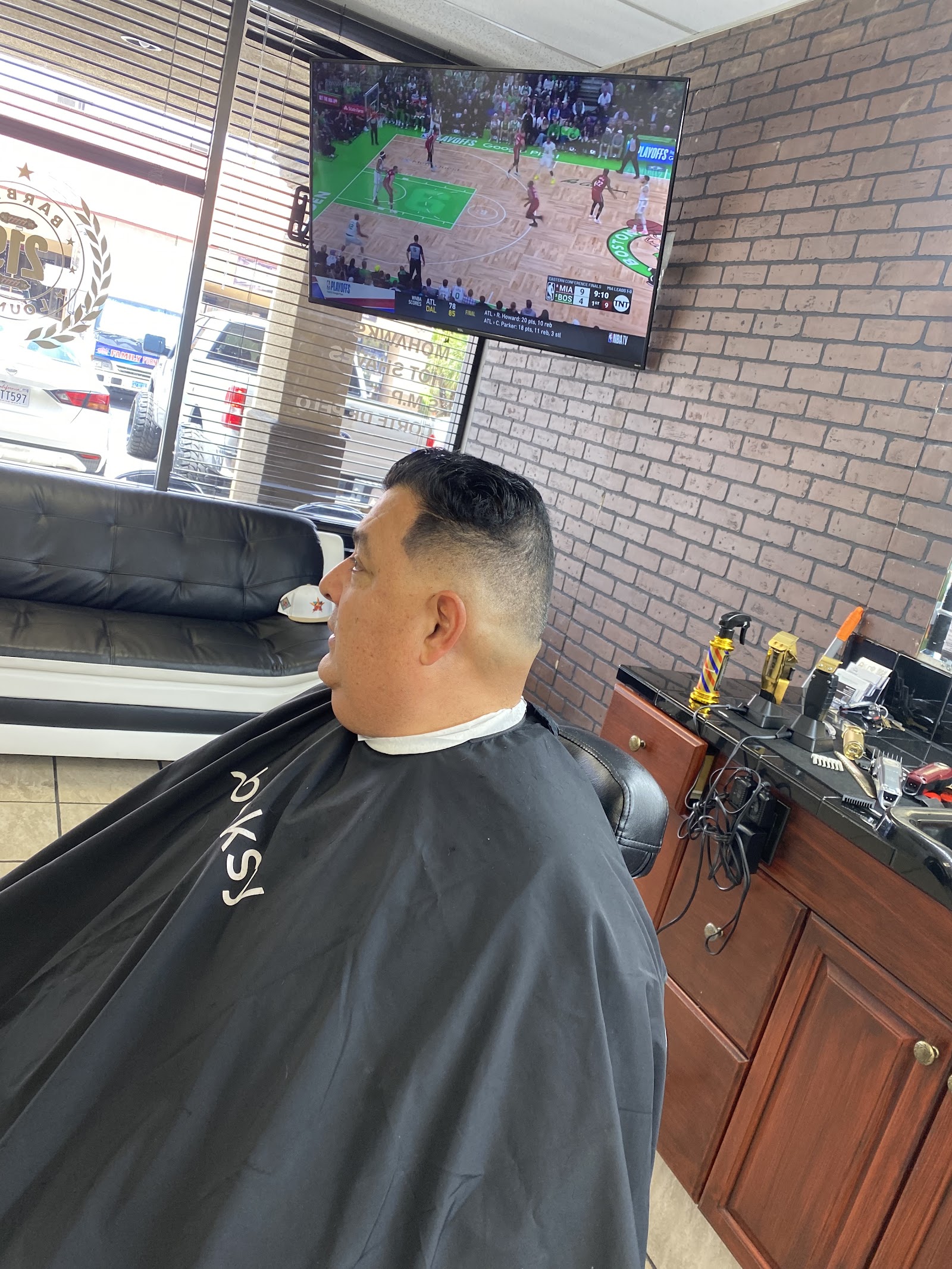 Man with fresh fade haircut seated in barber chair watching TV