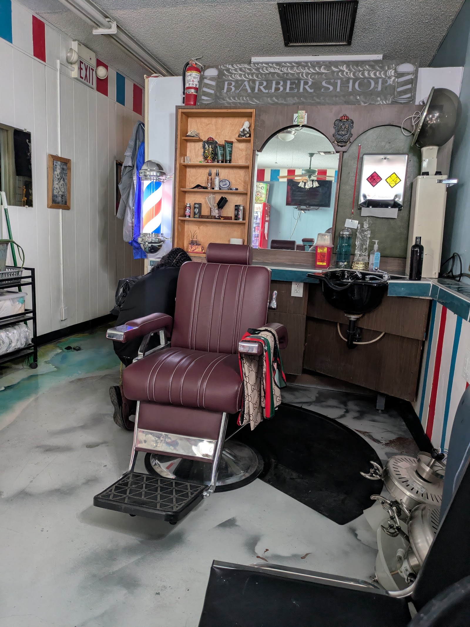 Vintage barber chair under 'Barber Shop' metal sign with mirror station and hood dryer