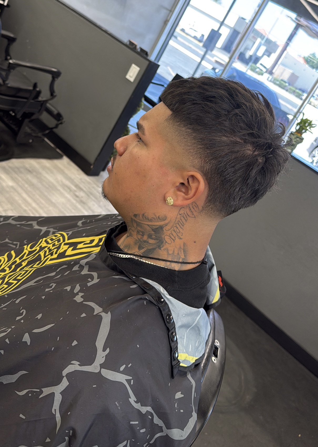 Side view of client with textured fade and neck tattoos after haircut