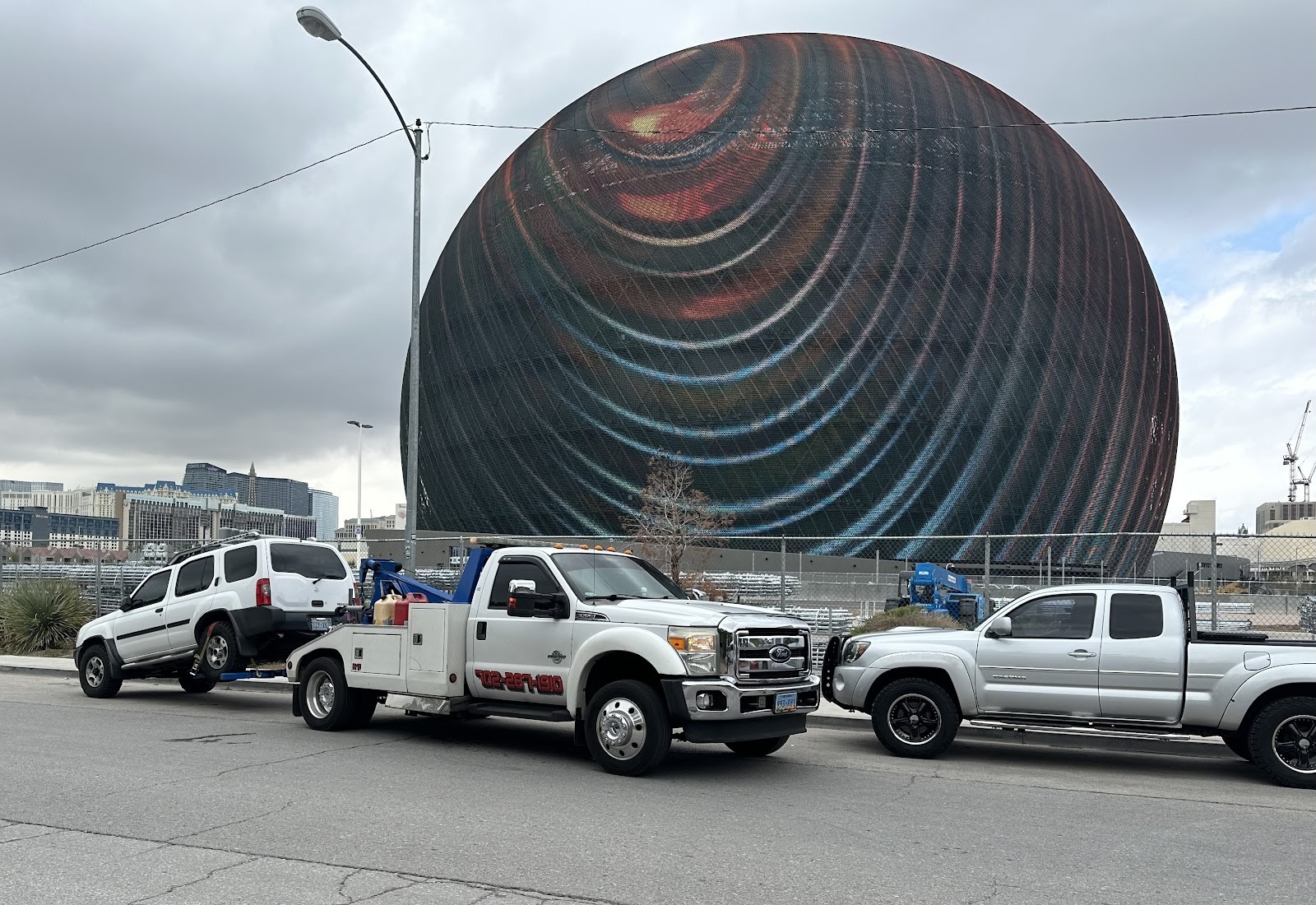 Ford tow truck with SUV loaded in front of the Las Vegas Sphere