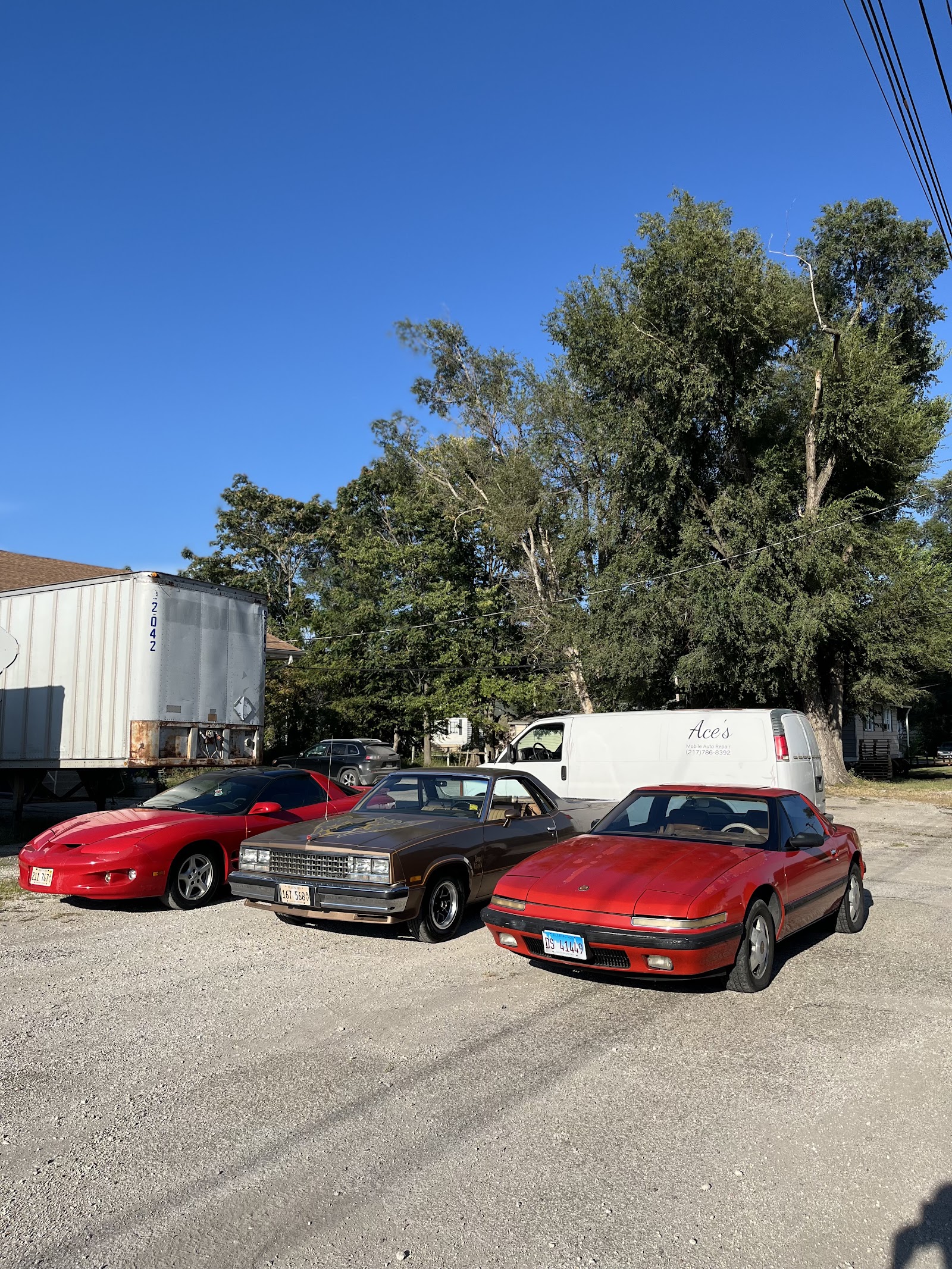 Three classic cars parked on gravel with Ace's Mobile Auto Repair van in background
