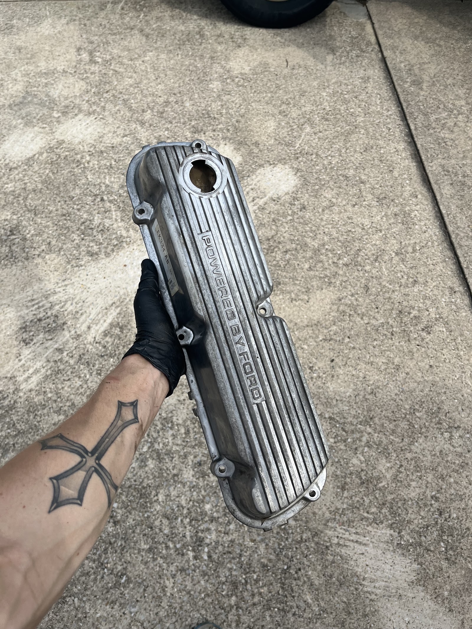 Mechanic holding a 'Powered by Ford' aluminum valve cover