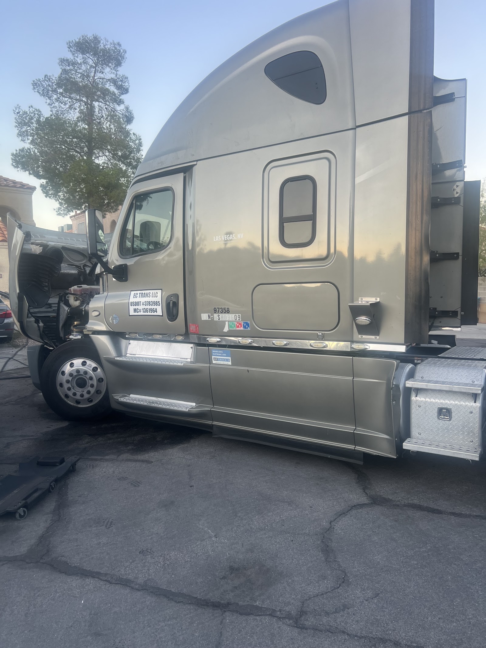 Freightliner semi truck with hood open being serviced roadside