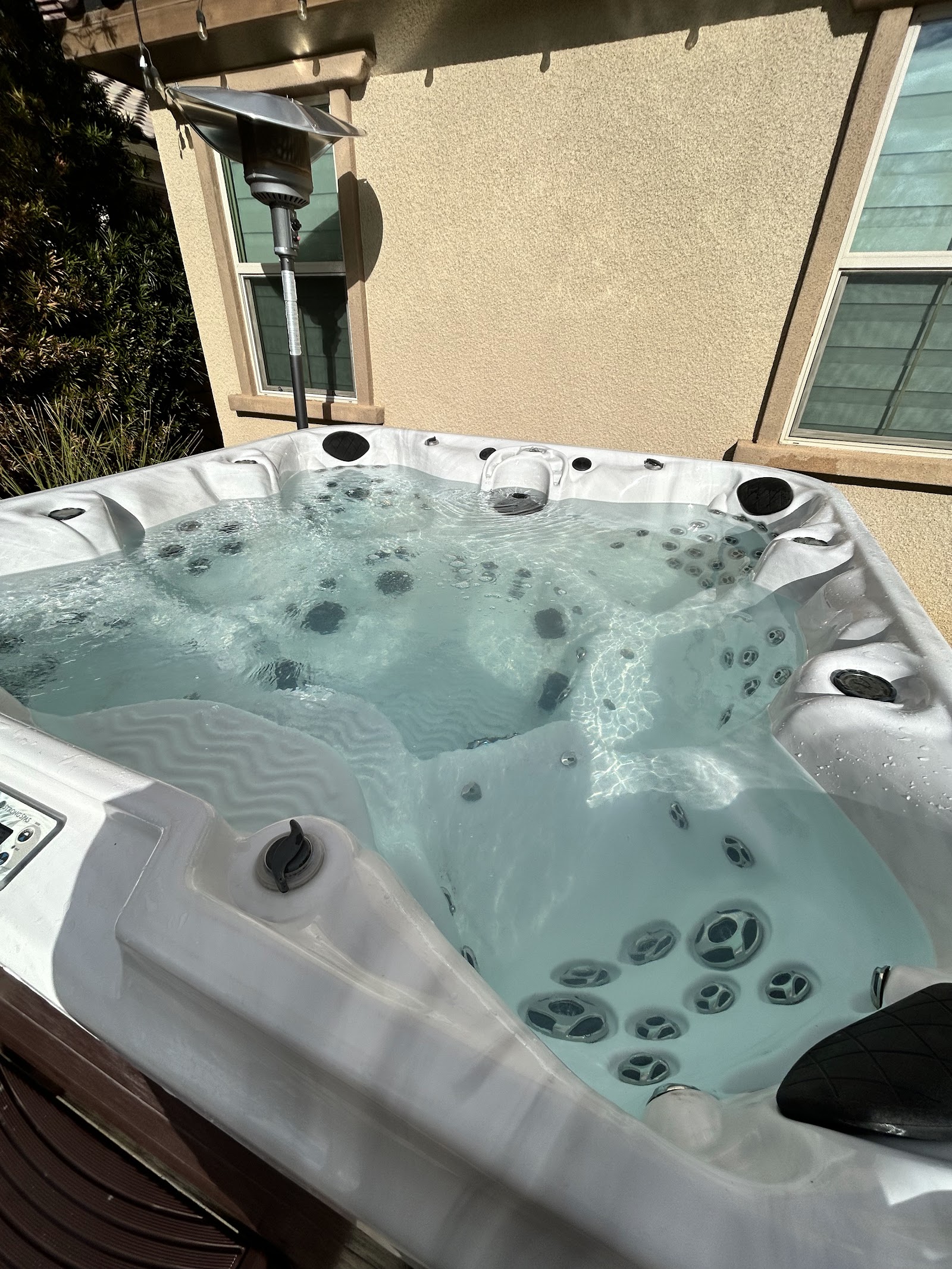 Bubbling hot tub with clear water beside a stucco home