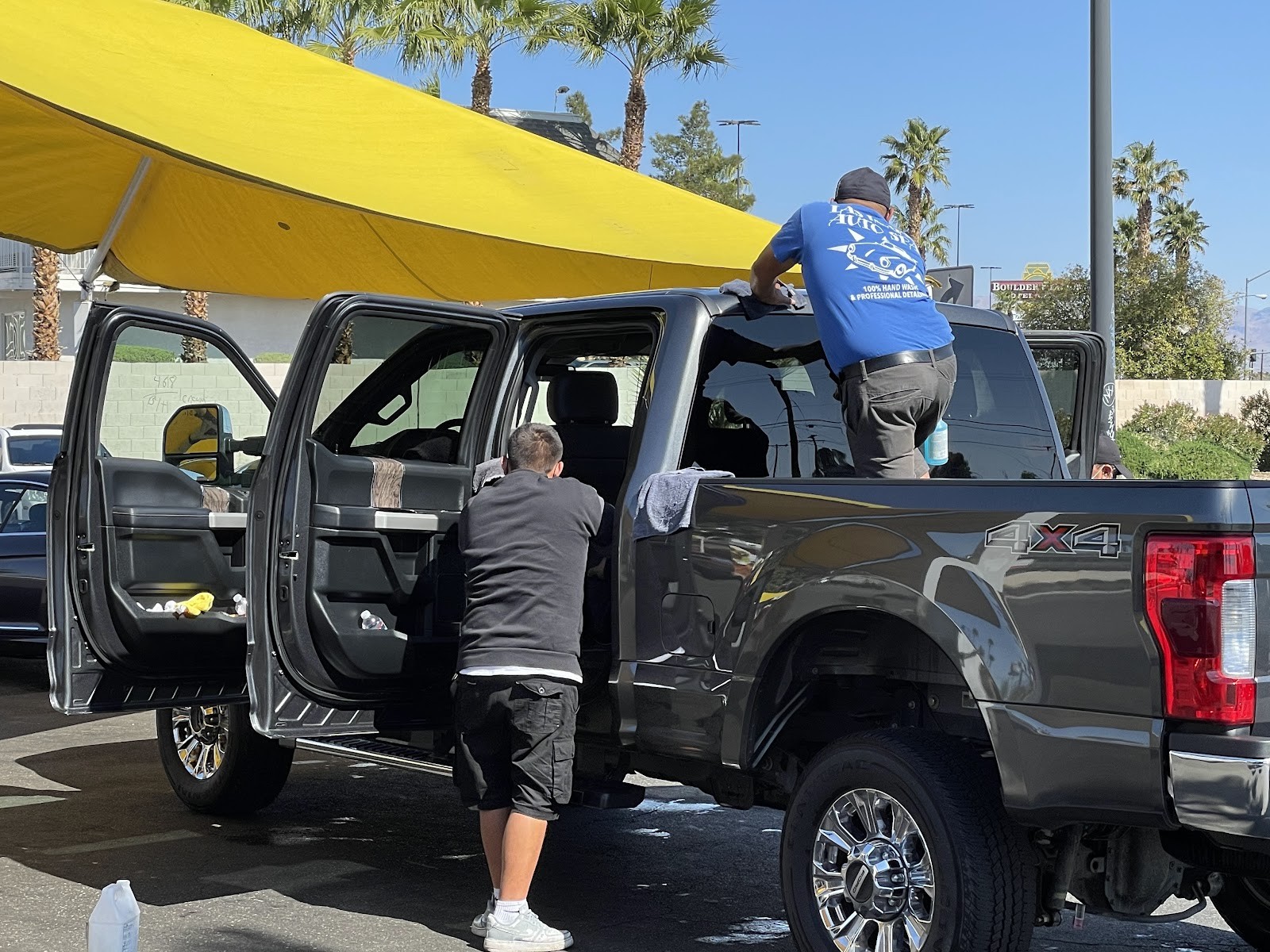 Two staff members hand-washing a gray Ford F-250 4x4 truck