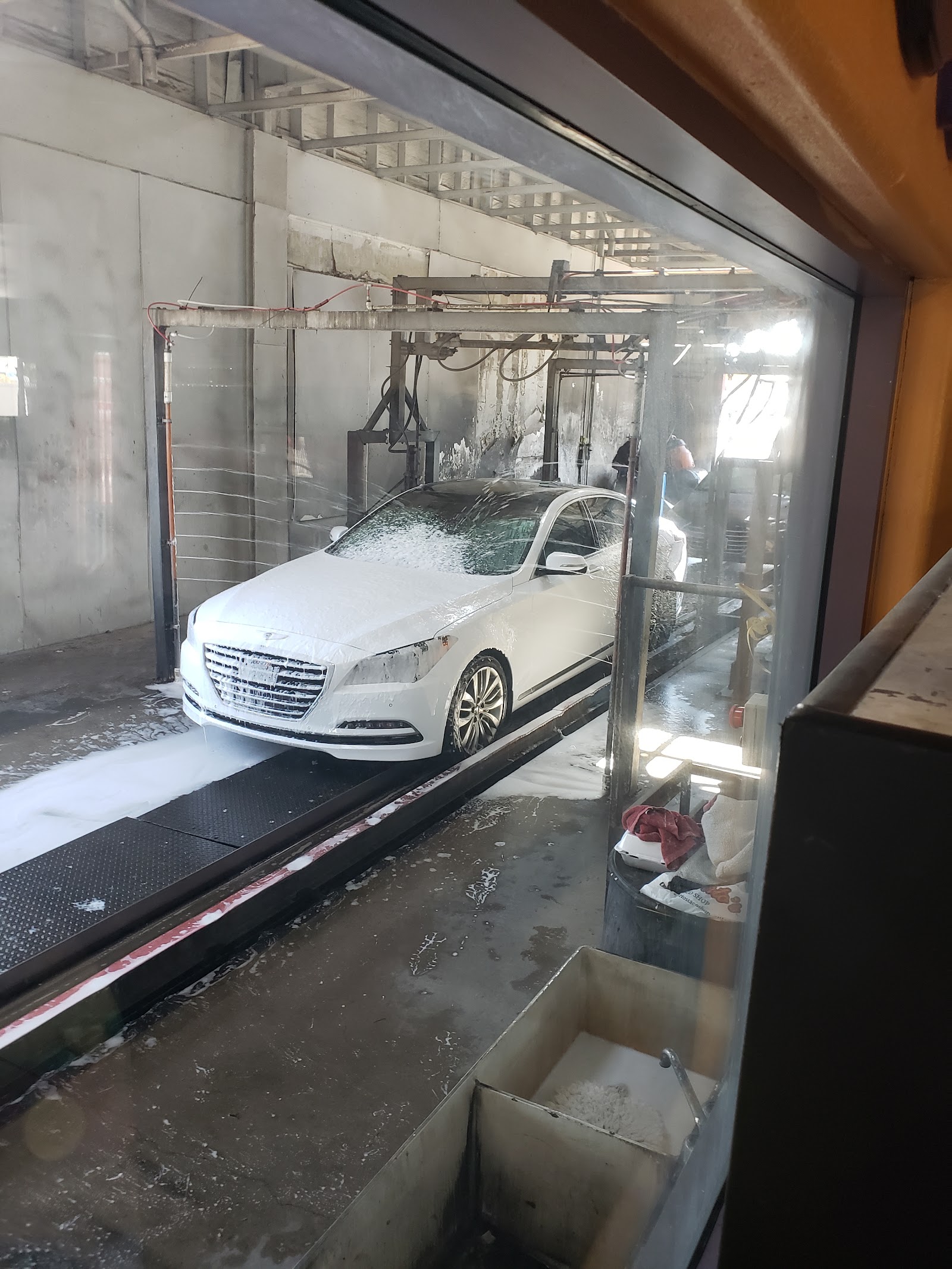 White sedan covered in foam inside the wash tunnel