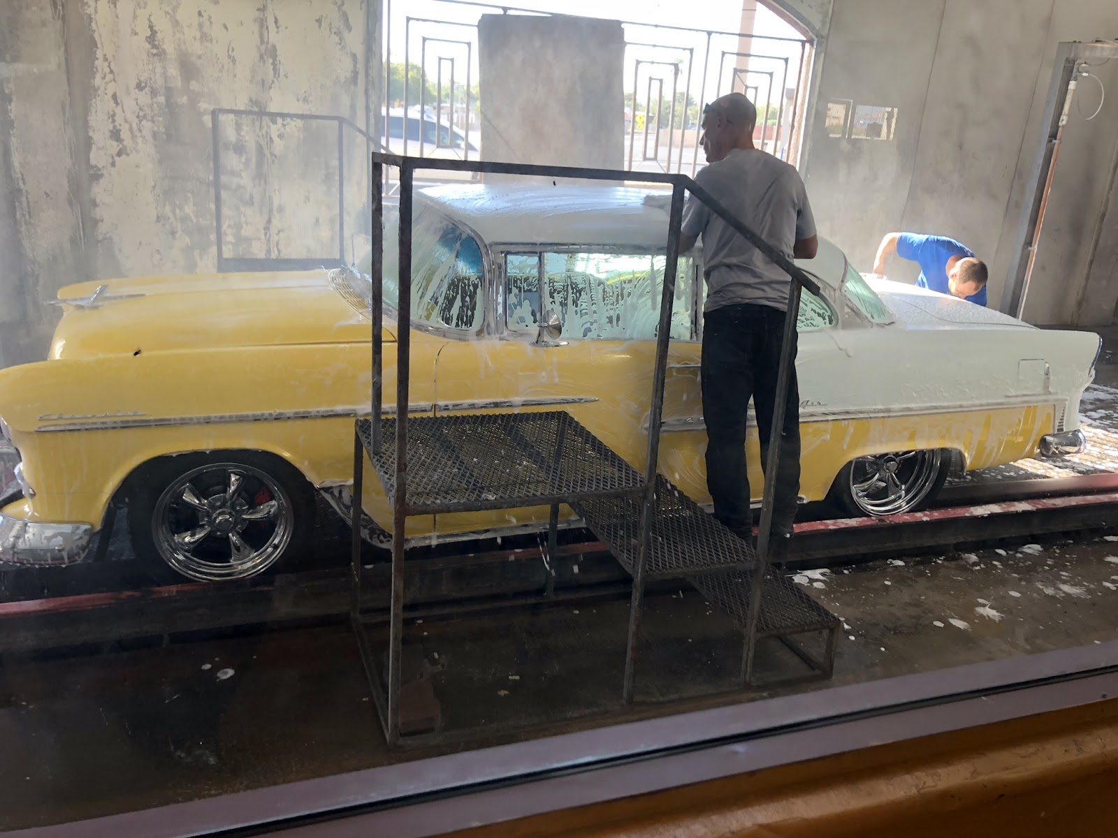 Workers hand-washing a classic yellow and white Chevrolet