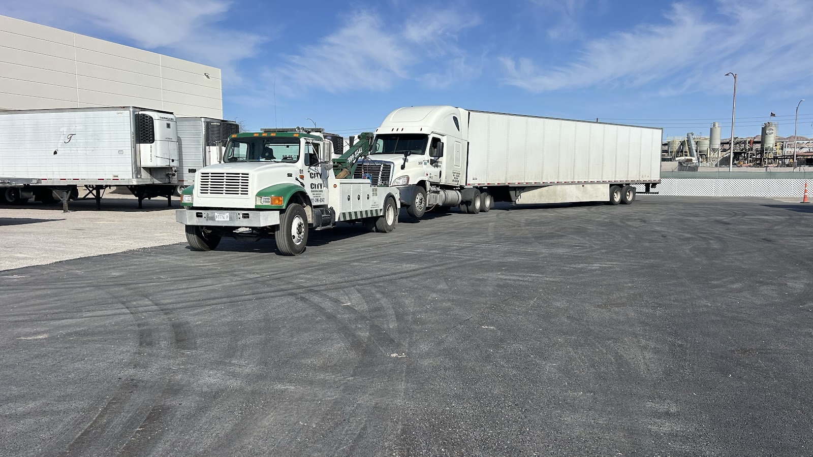 City 2 City wrecker towing a semi-truck with trailer in a paved lot