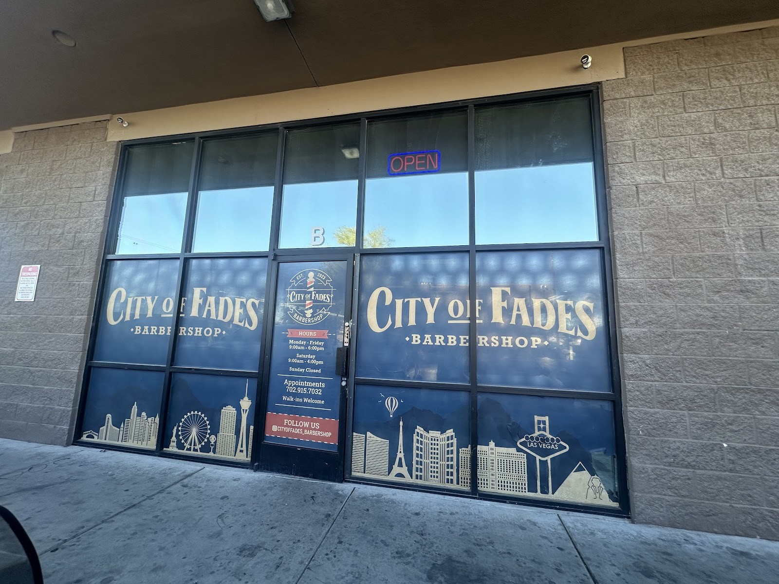 City of Fades Barbershop storefront windows with branding and OPEN sign