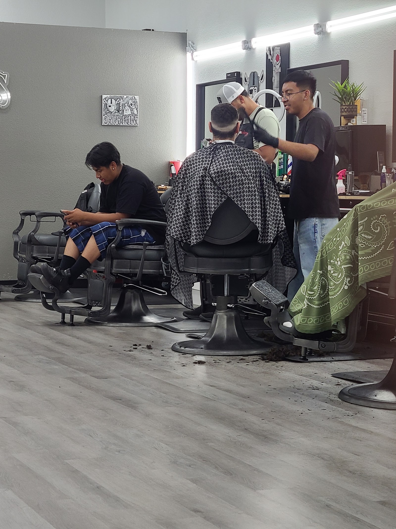 Barbers working on clients inside City of Fades with barber chairs and waiting area