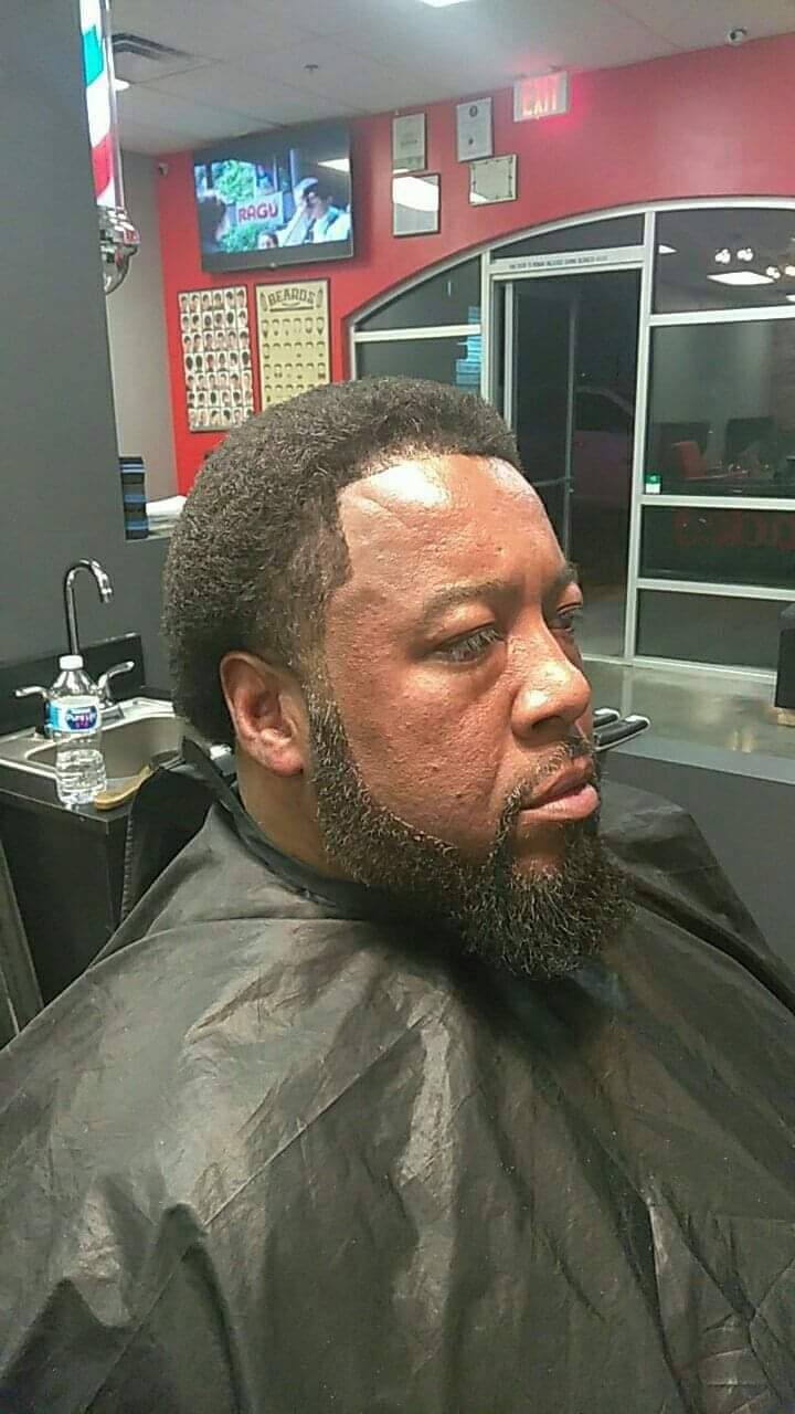 Man with sharp beard line-up and haircut in barber chair