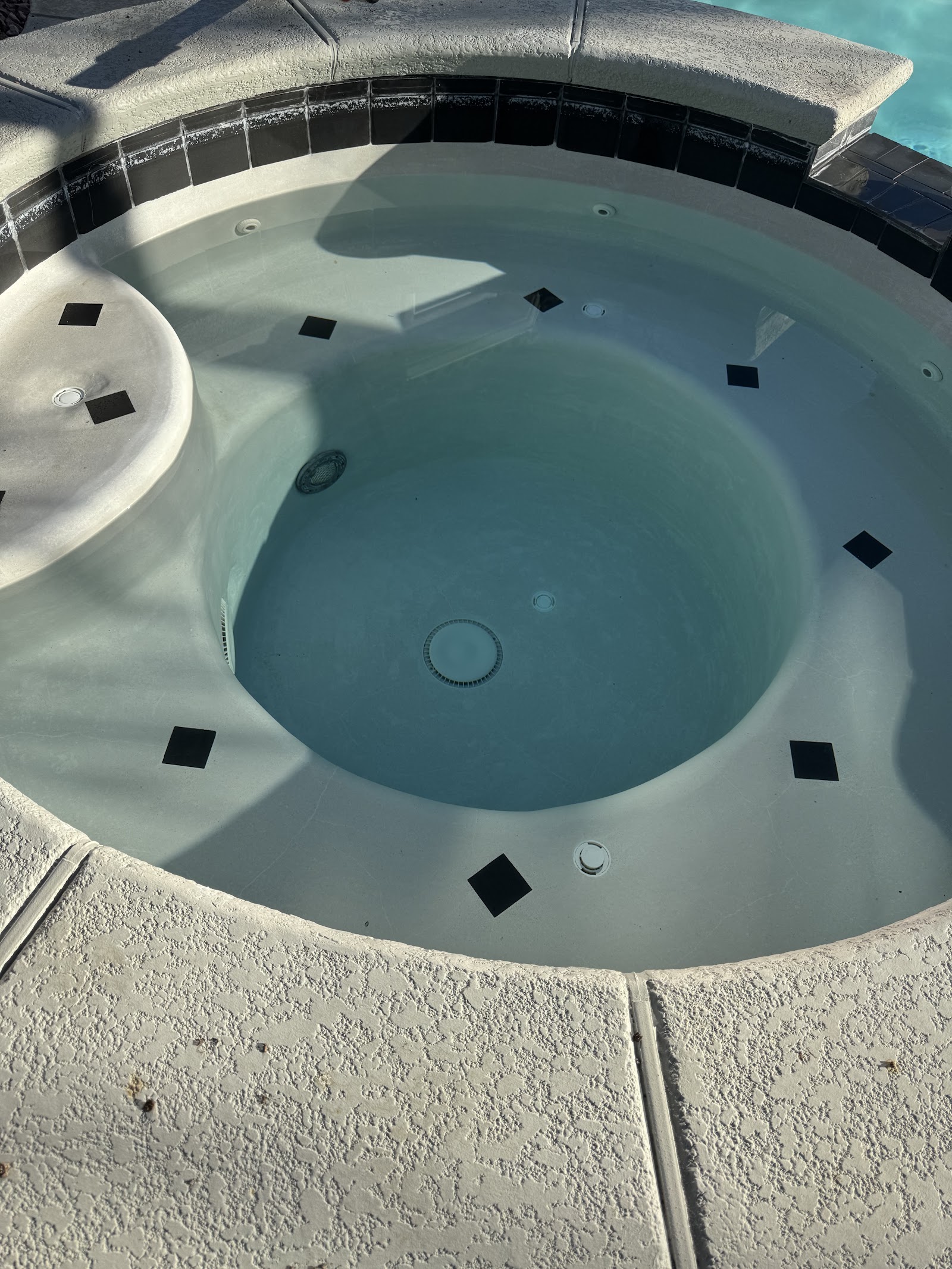Clean circular spa with black accent tiles and clear water