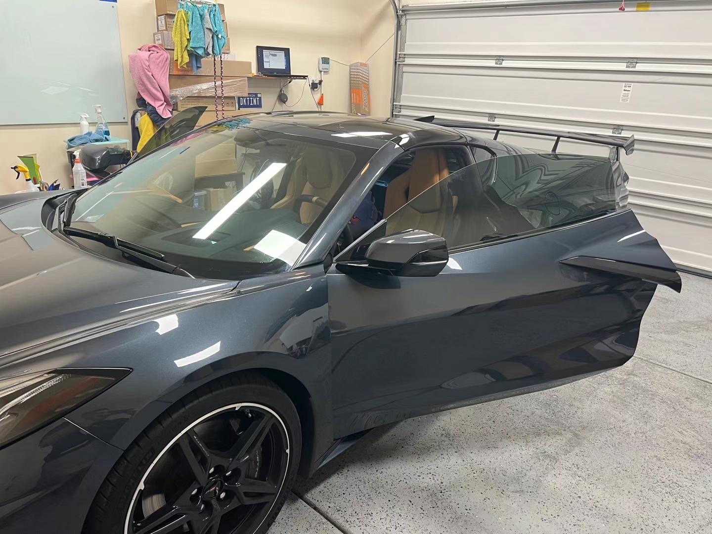 Dark gray Corvette with tinted windows and door open in the shop