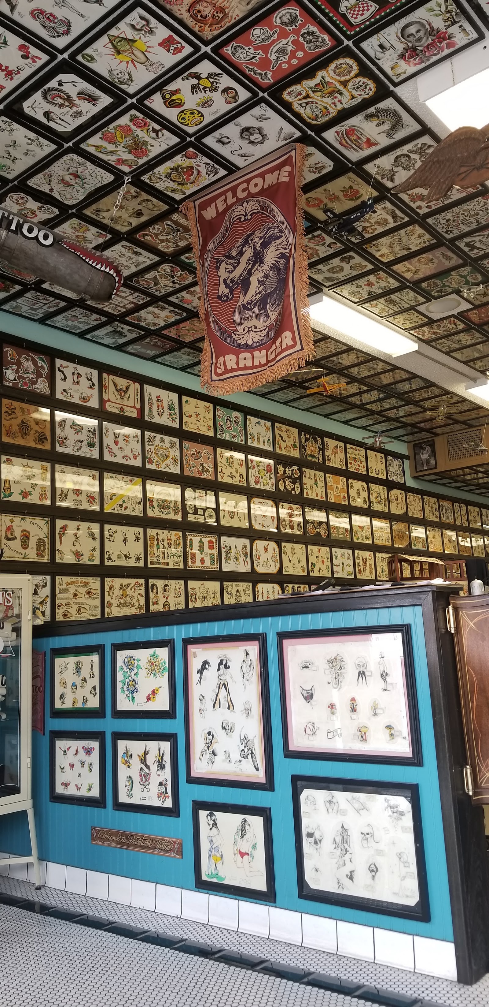 Barbershop interior with walls and ceiling covered in vintage tattoo flash art and a welcome banner