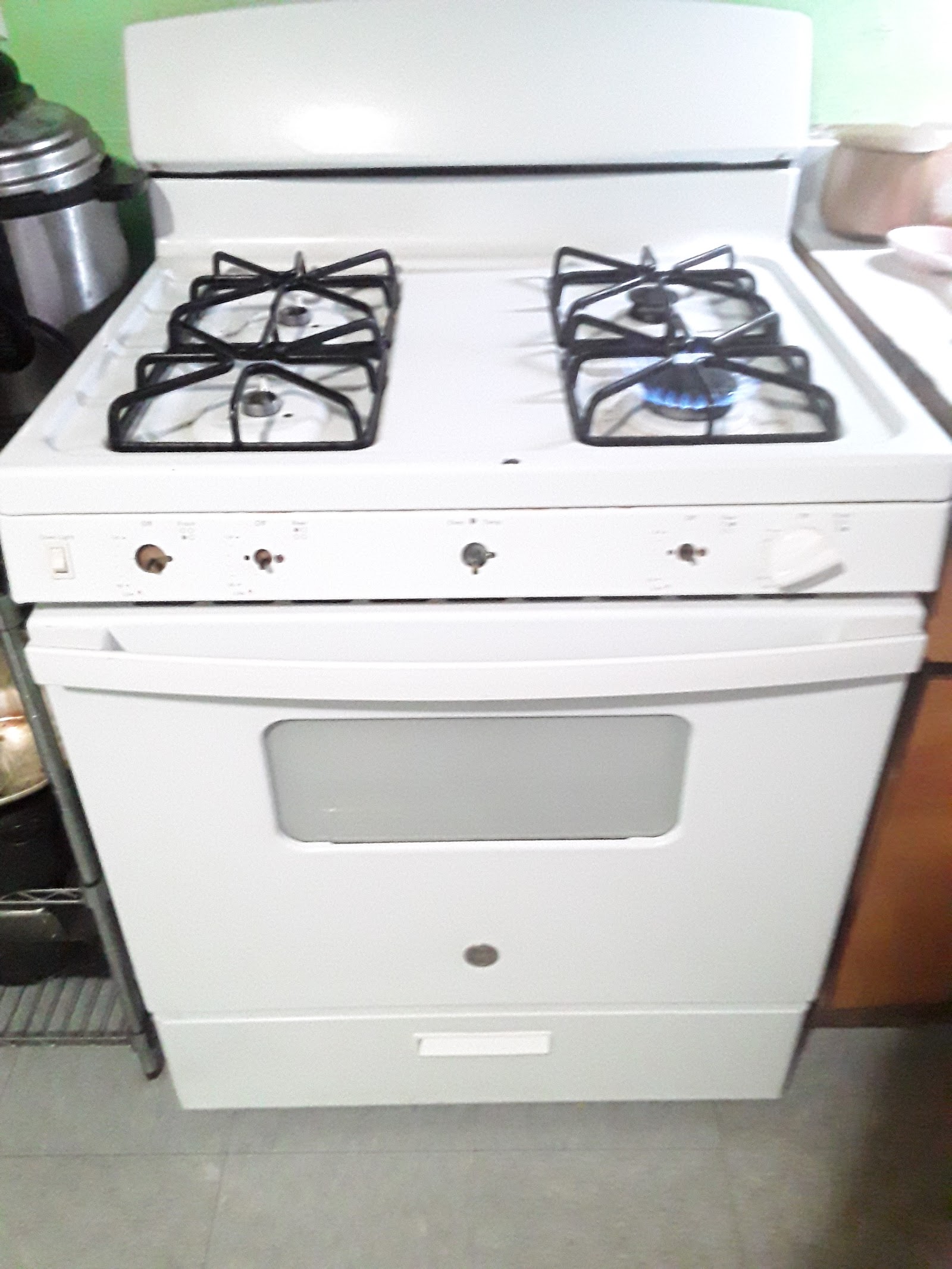 White gas range with lit blue burner flame