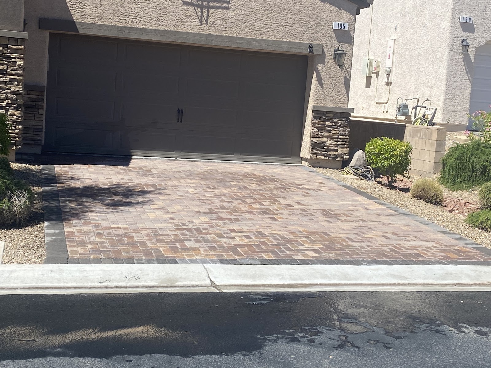 Freshly cleaned paver driveway in front of two-car garage