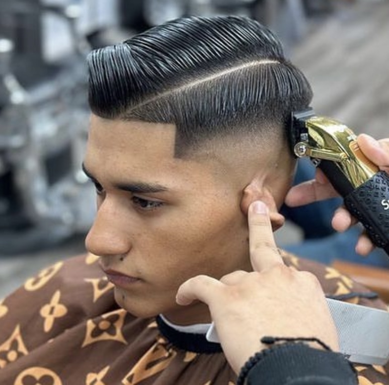 Man receiving a slick pompadour with hard part and skin fade