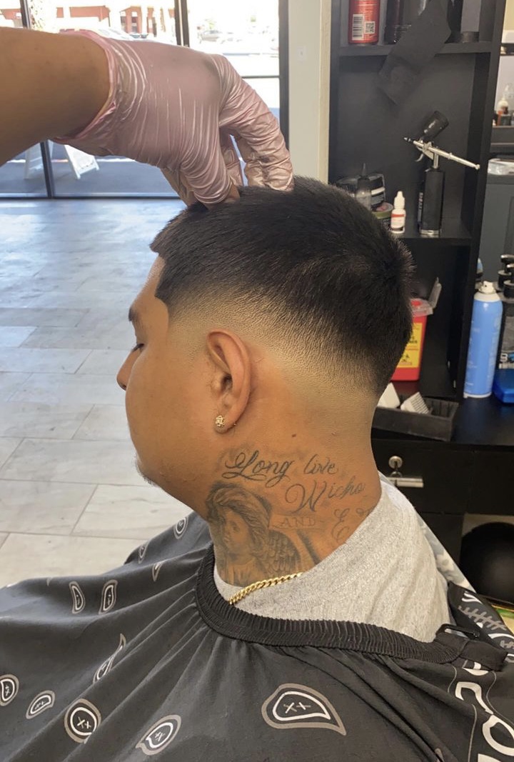 Back view of man's fresh taper fade with neck tattoo during cut