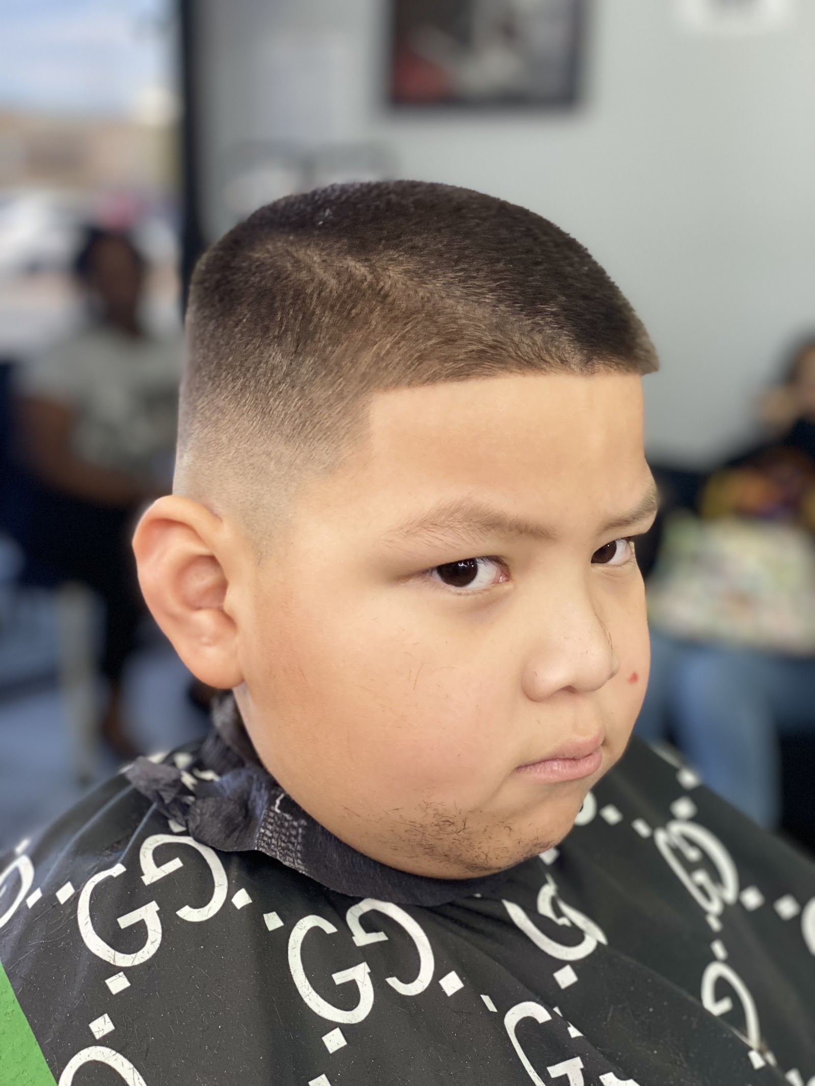 Young boy with clean crew cut and line-up fade in barber cape