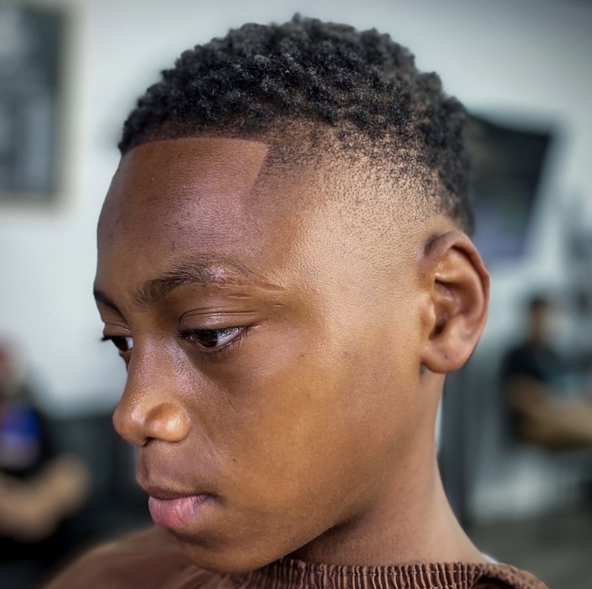 Side profile of young boy with curly top and clean fade with line-up