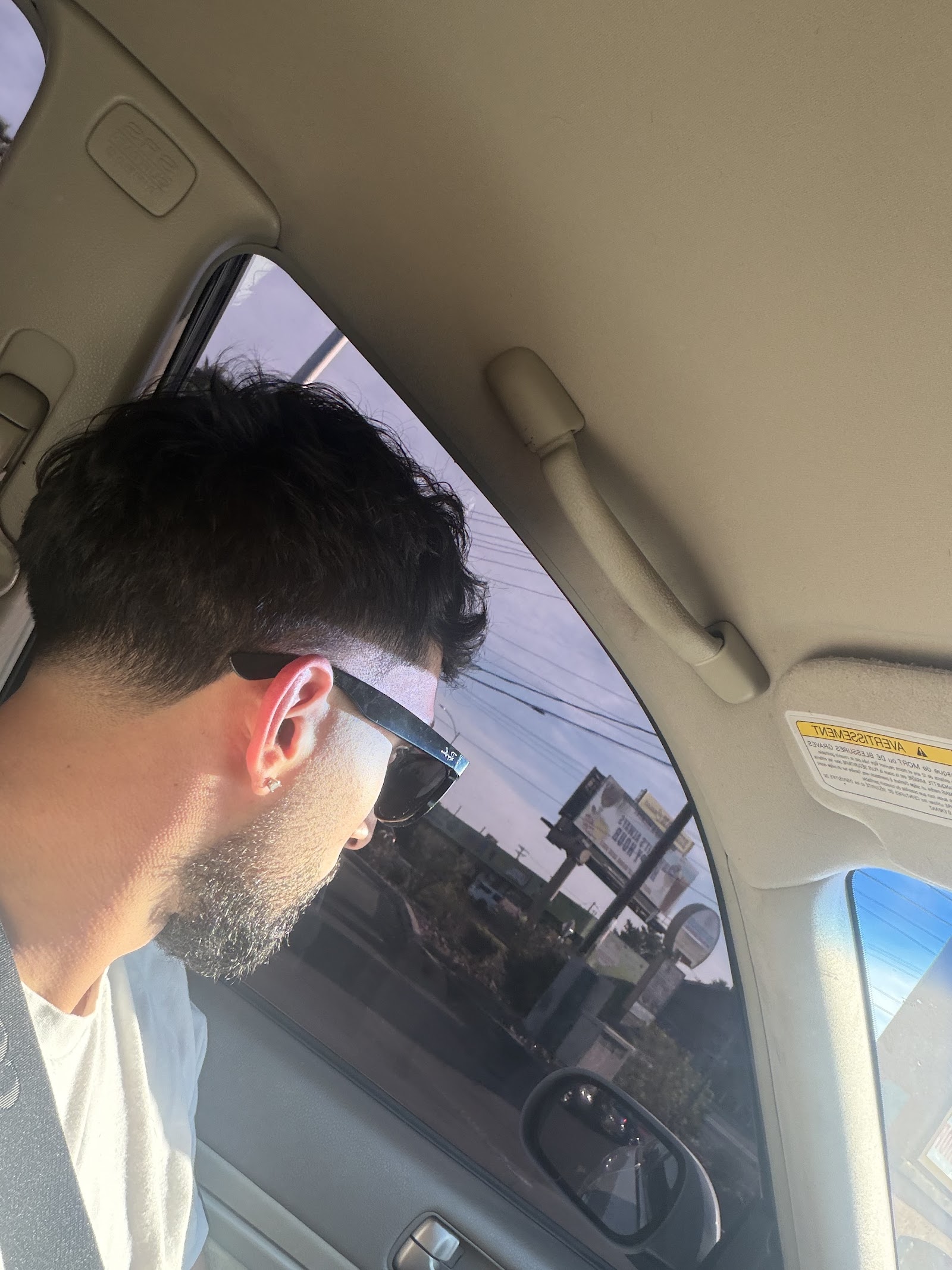 Man's textured taper fade haircut viewed from the side inside a car