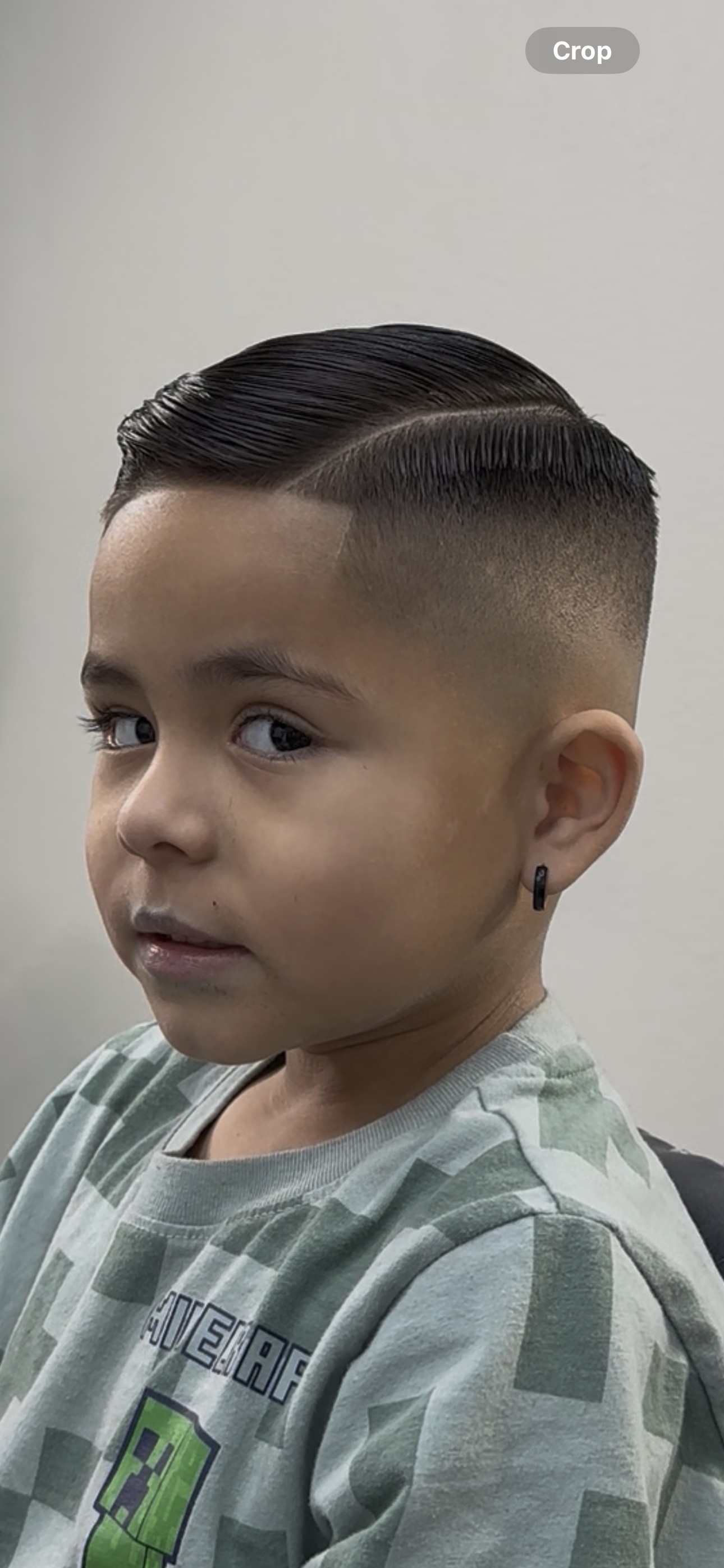 Young boy with a fresh side-part comb-over and high skin fade