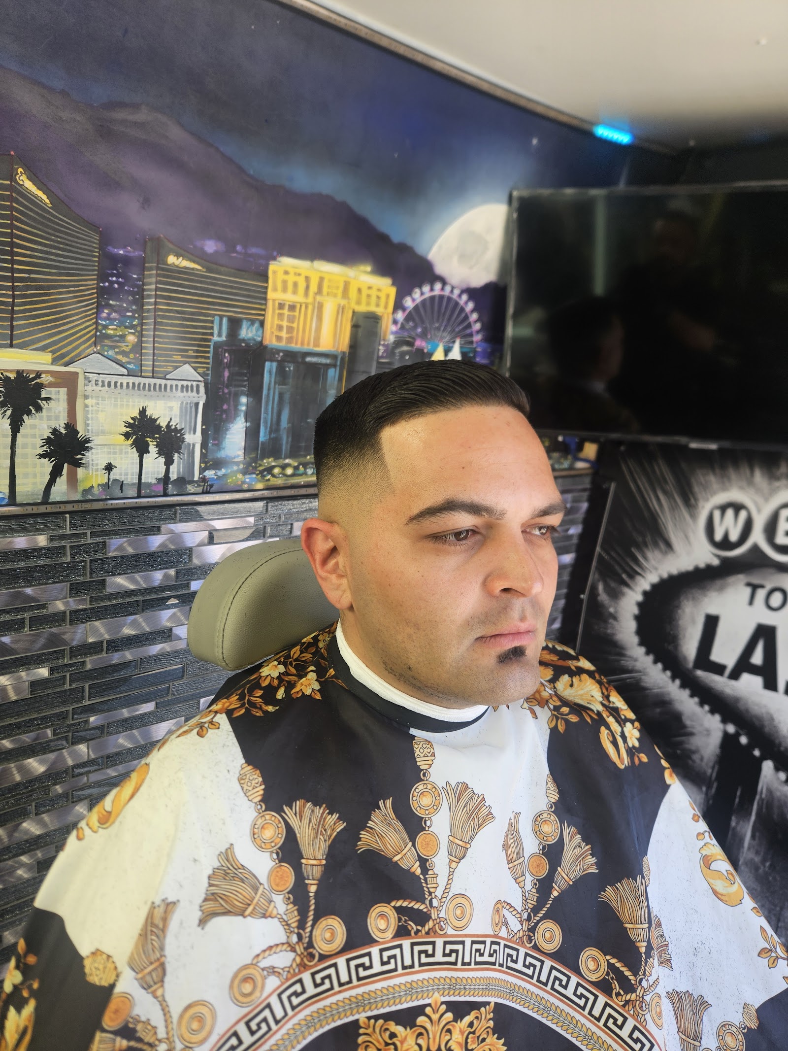 Client with fresh fade haircut seated in barber chair with Vegas skyline mural behind