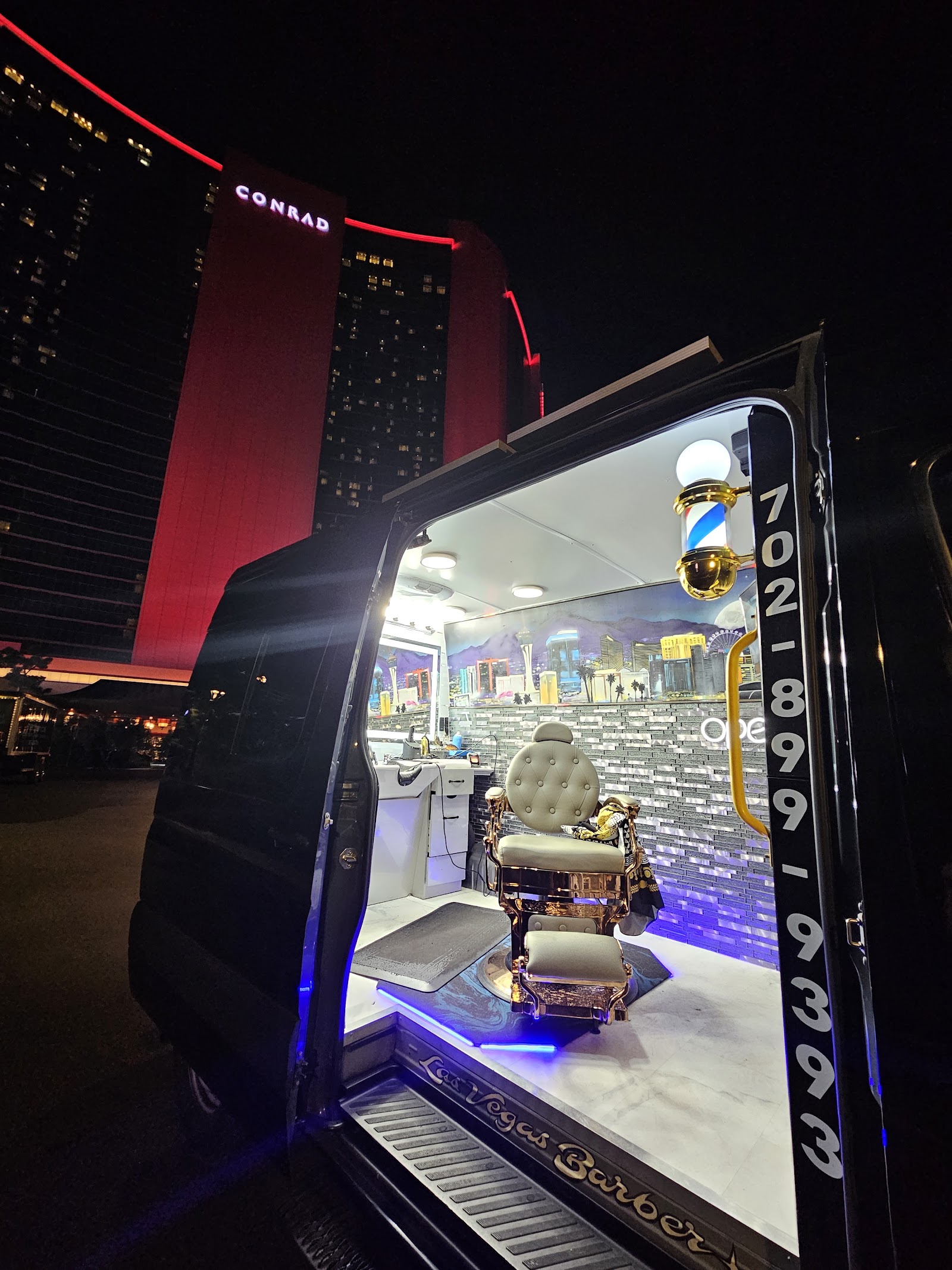 Mobile barbershop van open at night in front of the Conrad Las Vegas hotel