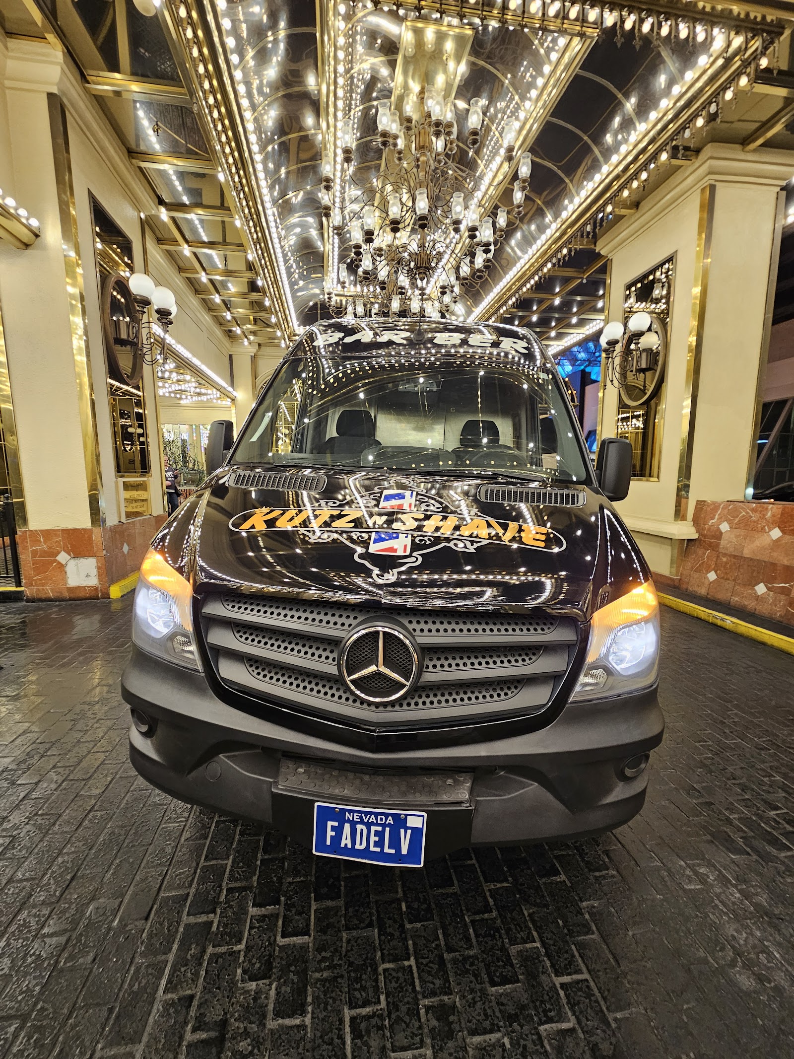 Front view of black Mercedes Sprinter barber van with 'Kutz N Shave' branding under casino lights