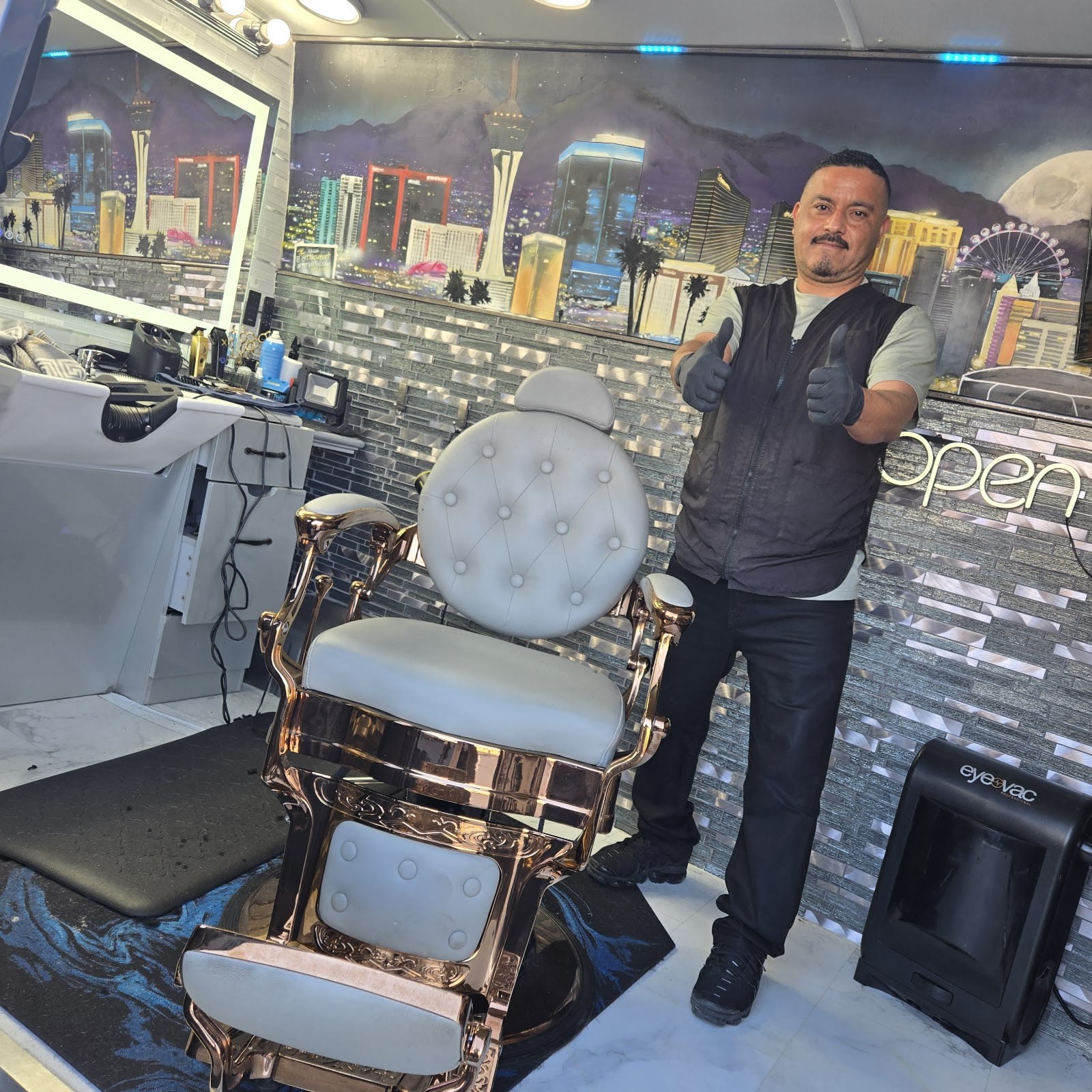 Barber giving thumbs up next to gold and white barber chair inside the van