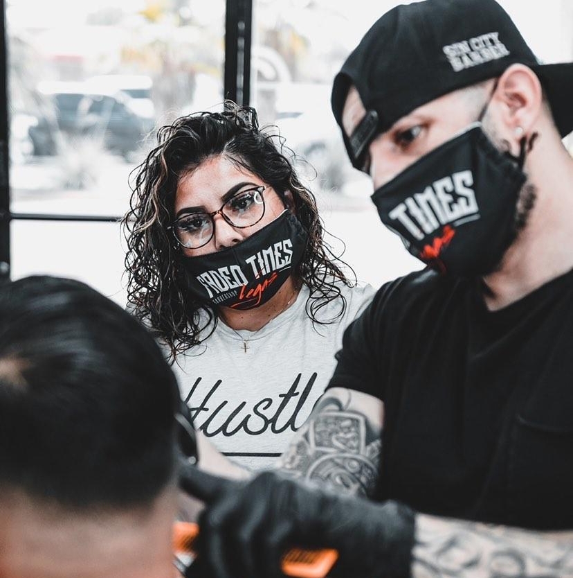 Two barbers in branded Faded Times masks working on a client