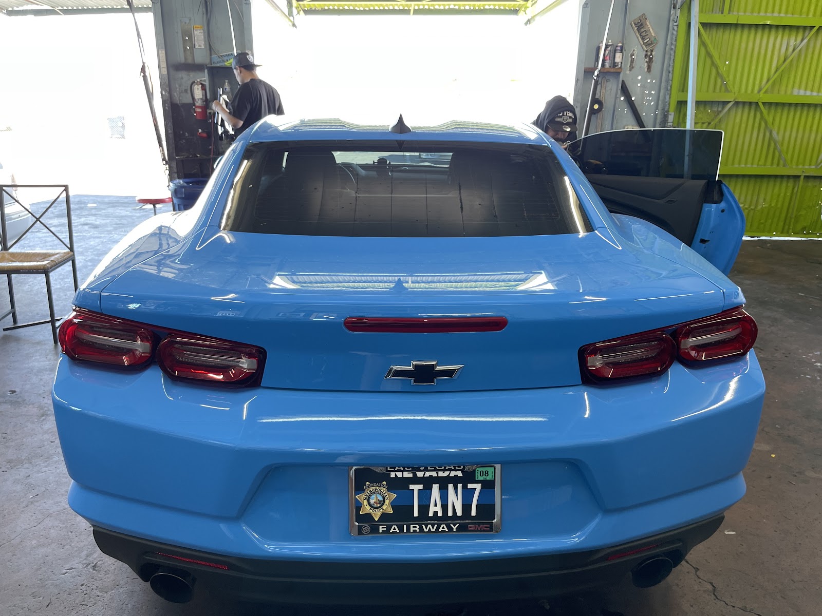 Rear view of blue Chevrolet Camaro with tinted rear glass inside shop bay