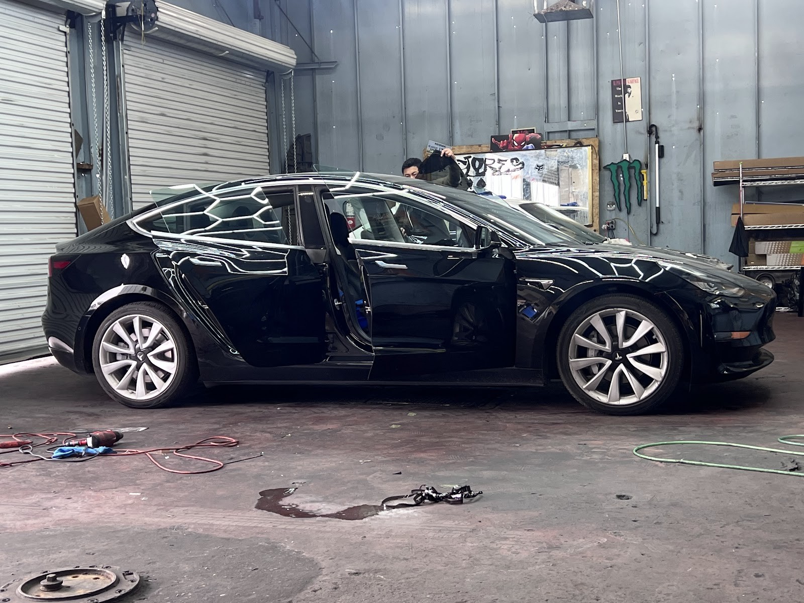 Black Tesla Model 3 with doors open during tint installation in the shop