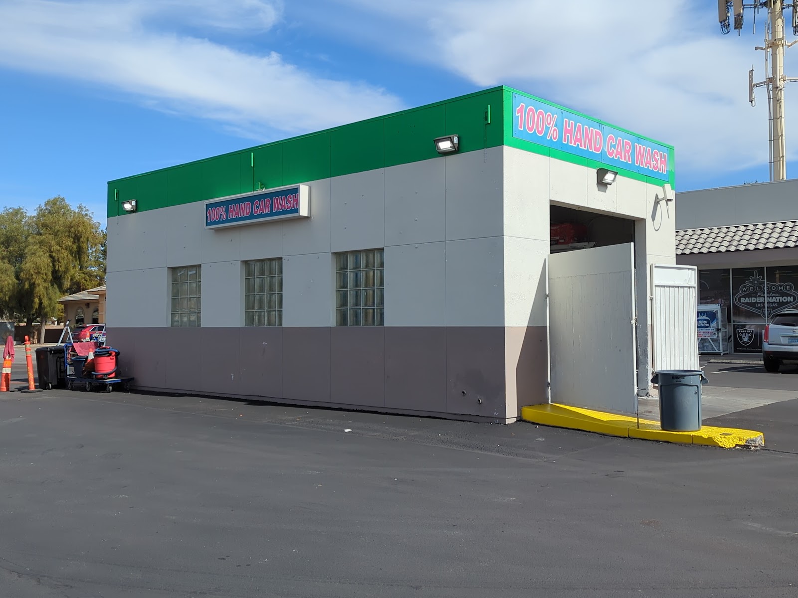 Exterior of 100% Hand Car Wash building with green and pink signage
