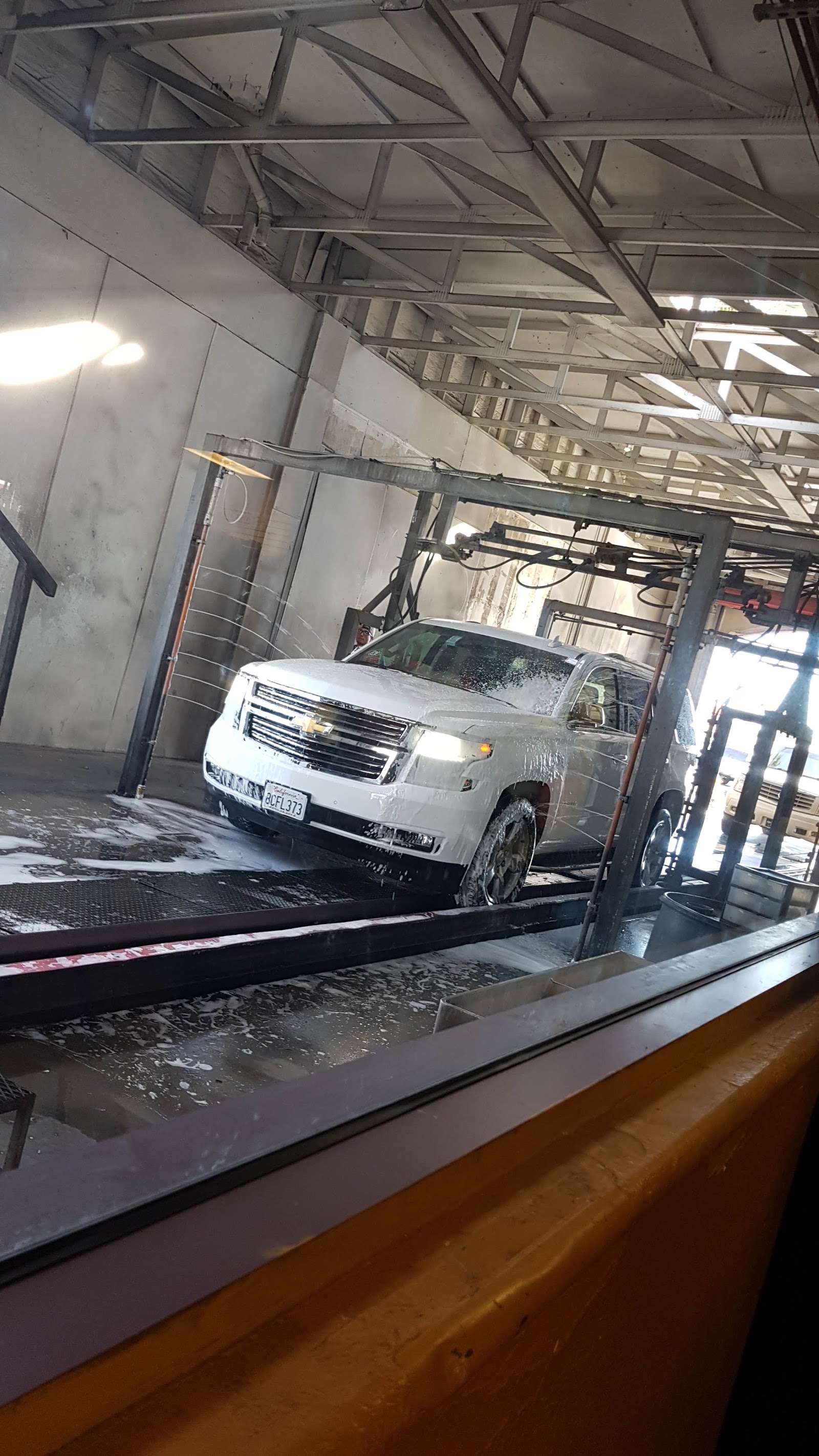 White Chevrolet SUV covered in soap inside car wash tunnel