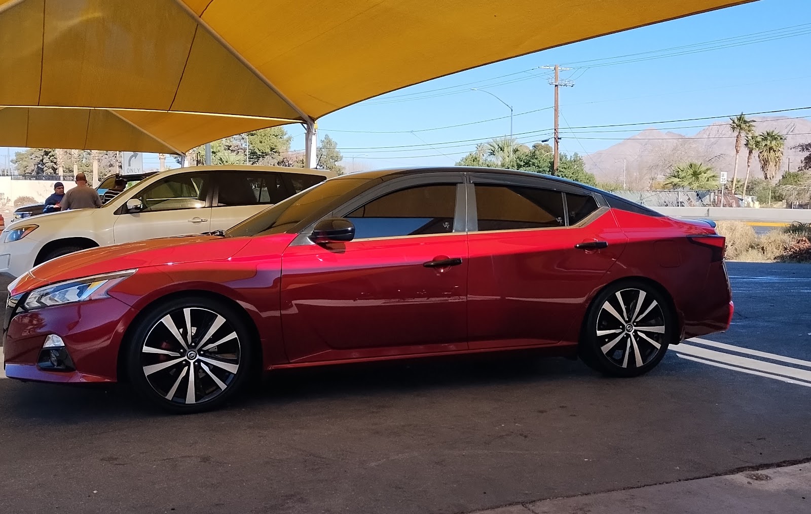 Side profile of clean red Nissan Altima under car wash canopy
