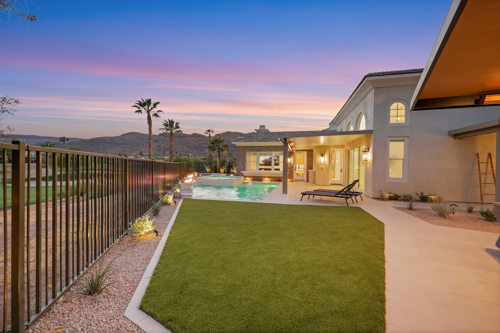 Backyard with turf lawn, pool and patio at sunset with golf course and mountain views