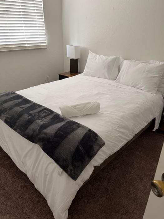 Neatly made bed with white bedding and folded towel