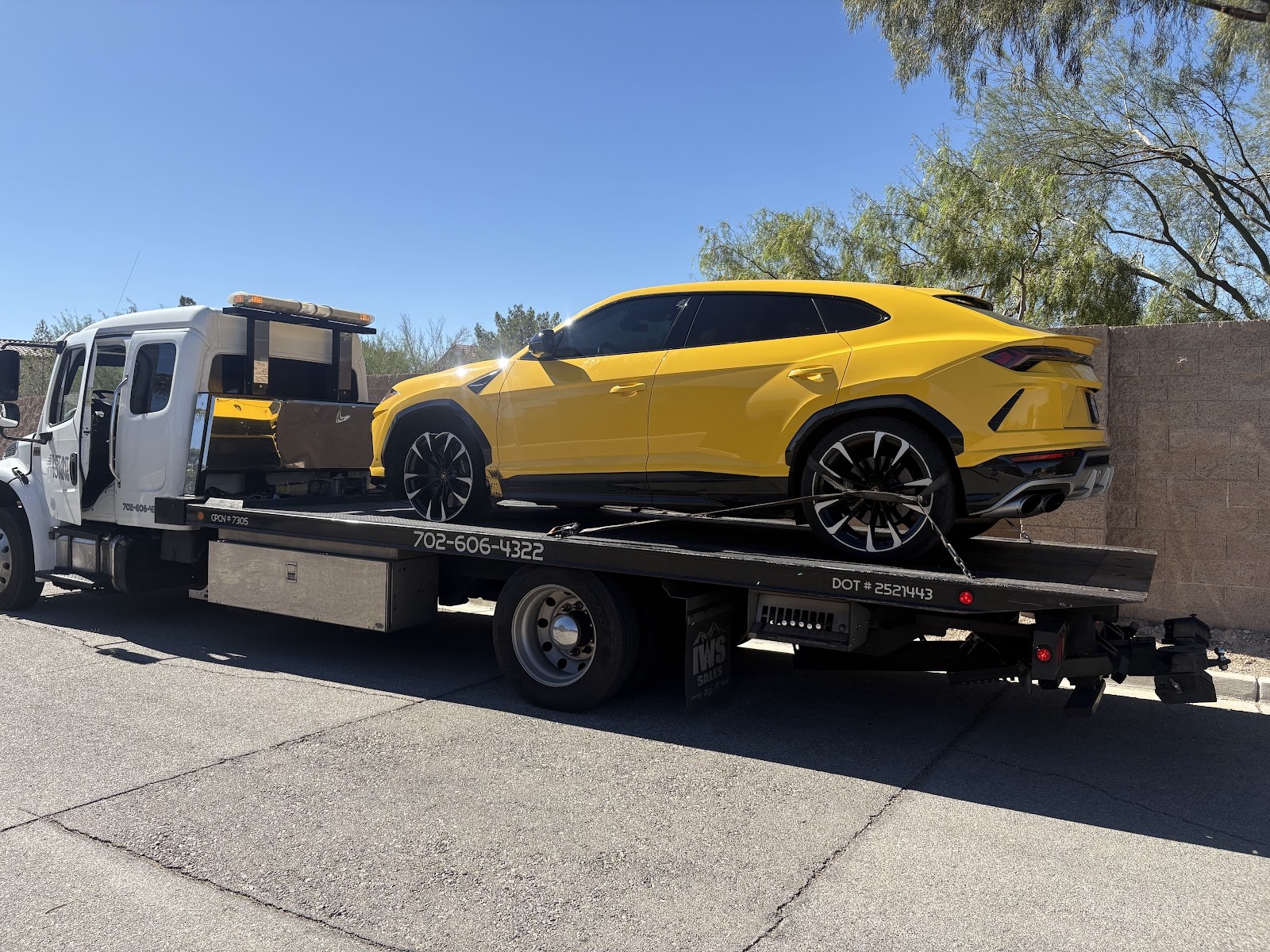 Flatbed tow truck transporting a yellow Lamborghini Urus SUV