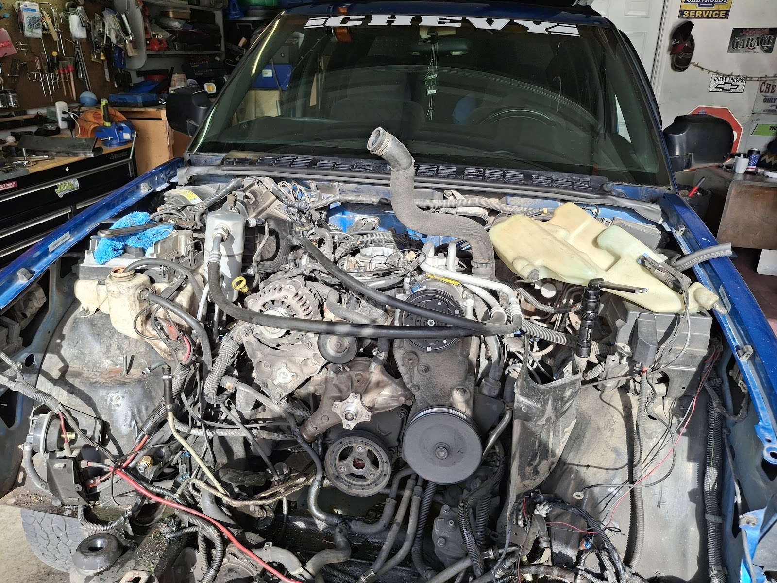 Engine bay of a Chevy truck mid-repair in a garage