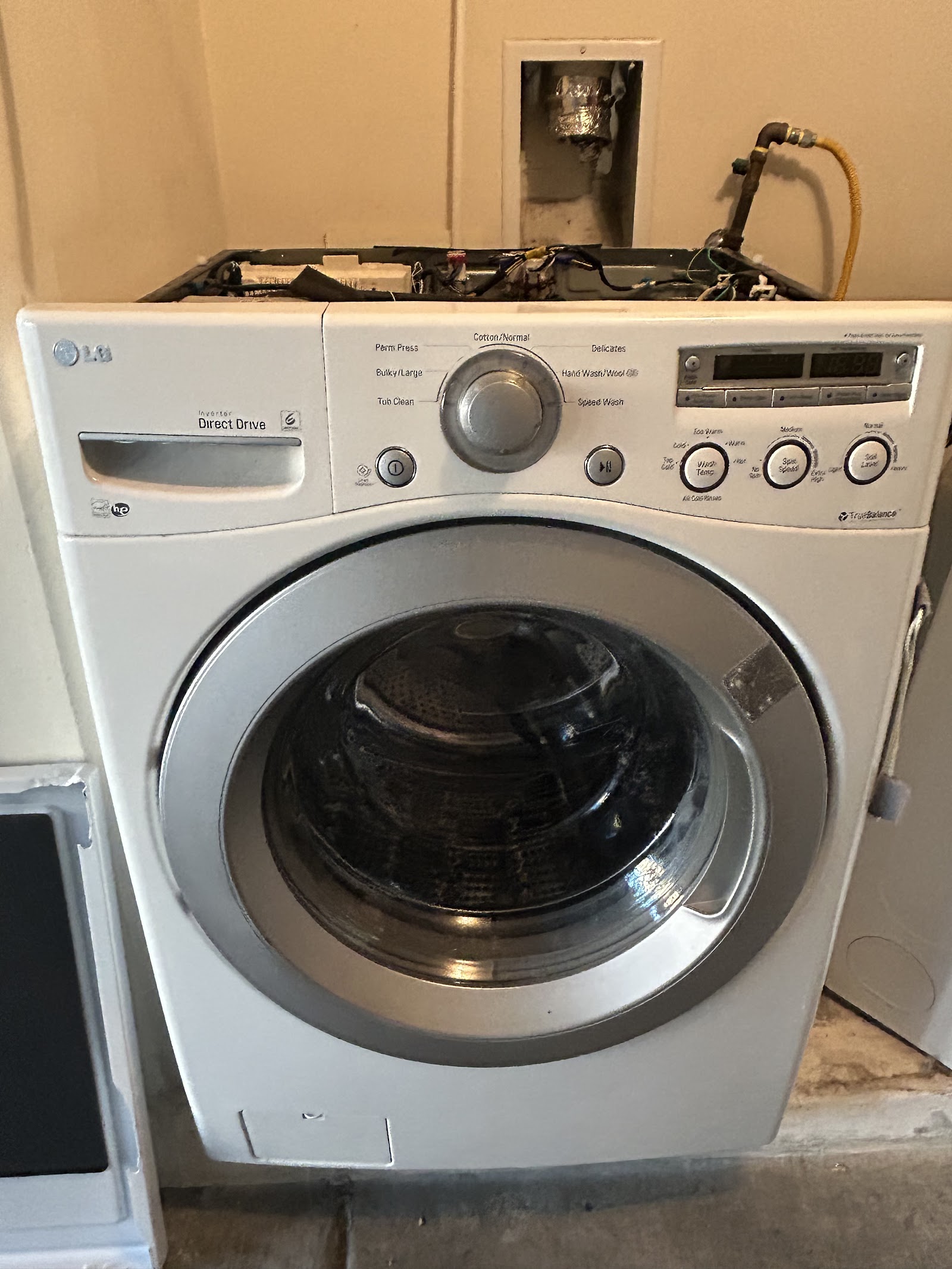 LG front-load washer with top panel removed exposing internal wiring during repair