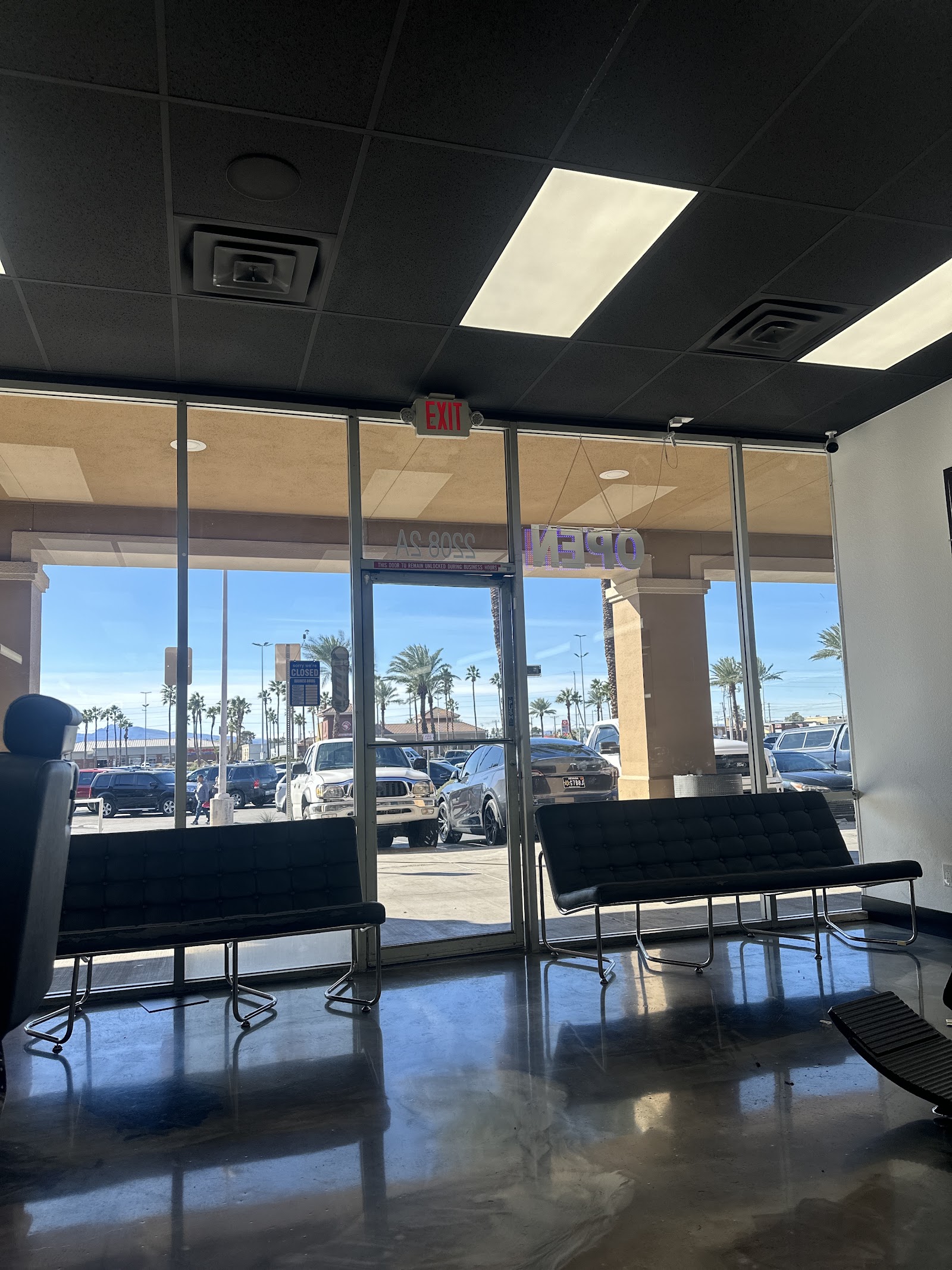 Barbershop waiting area with black benches and view of parking lot through glass storefront