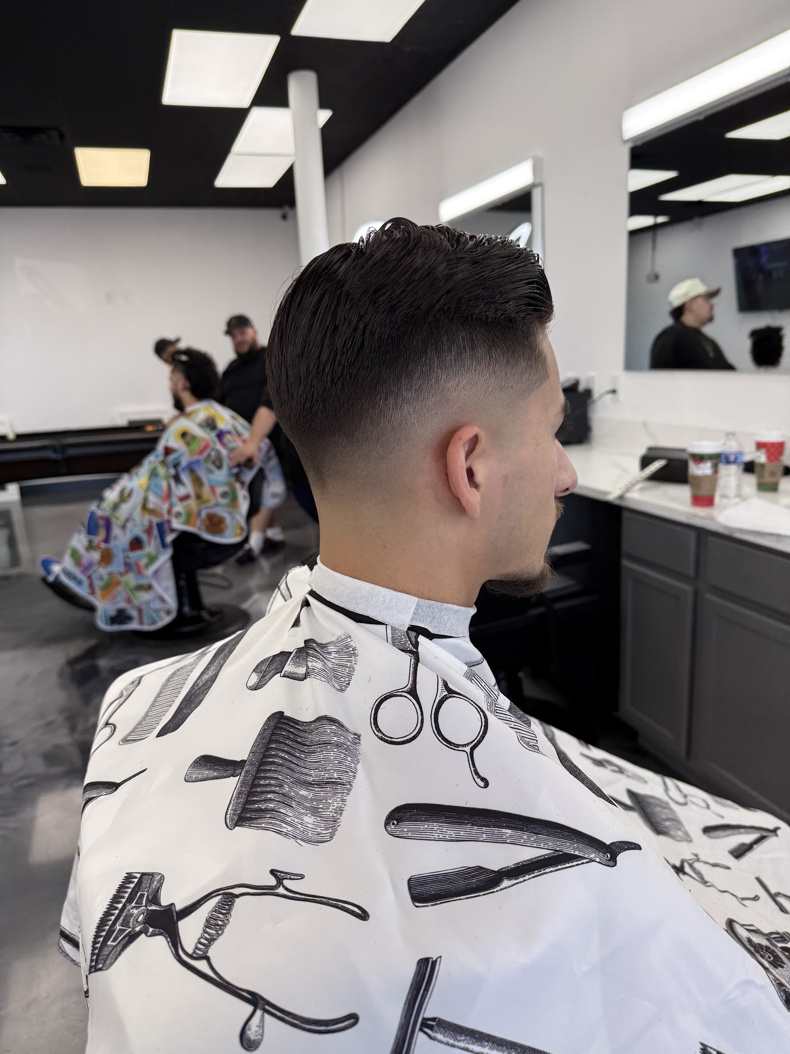 Client with fresh tapered fade and styled top in barber cape