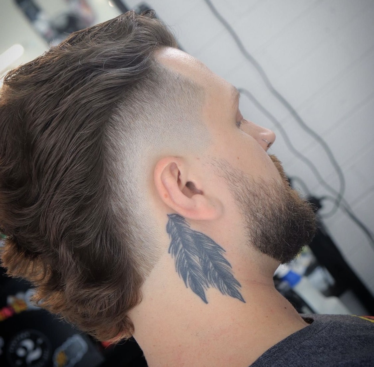 Man with long wavy mullet-style cut, skin fade sides and full beard