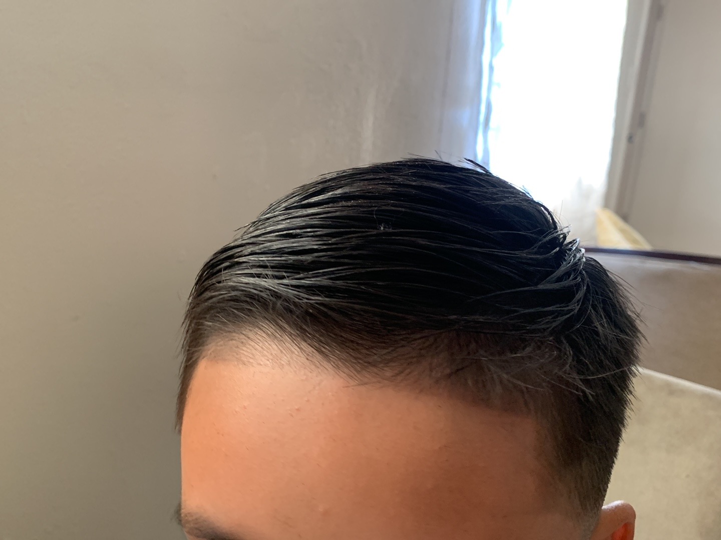 Top view of man's slicked-back dark hairstyle with faded sides