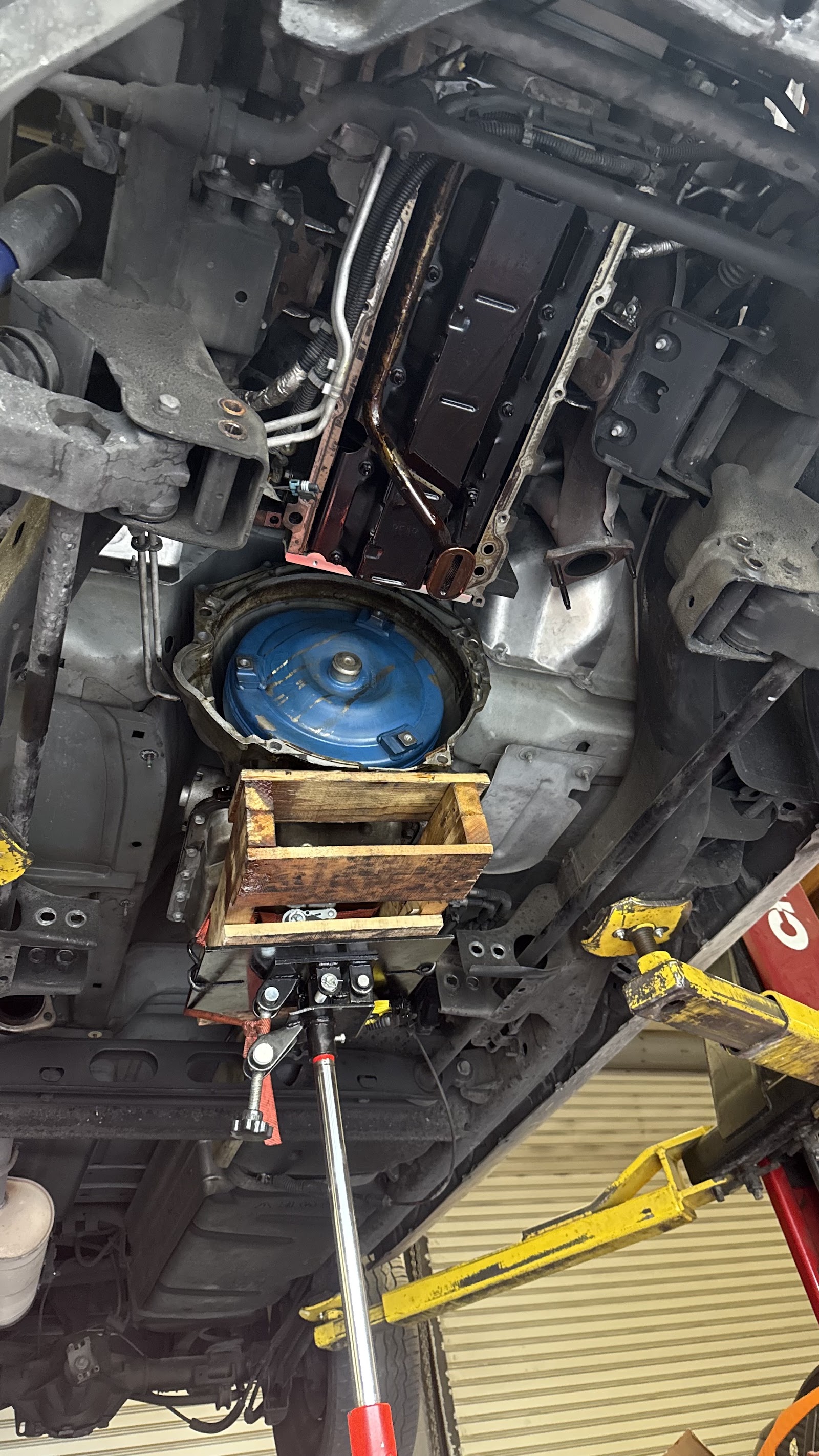 Transmission removal with torque converter exposed, supported on a transmission jack