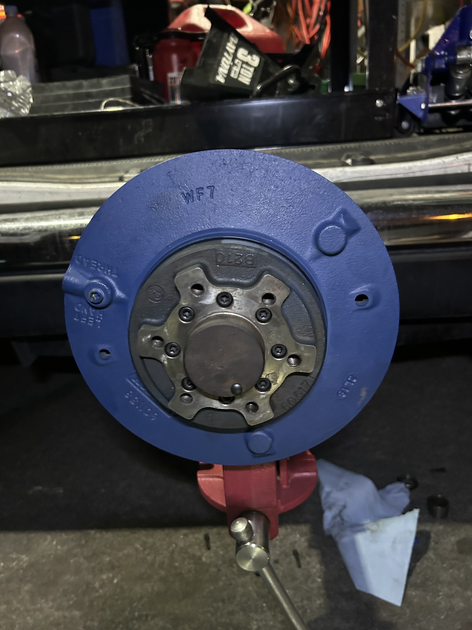 Freshly painted blue brake drum/hub assembly mounted in a bench vise