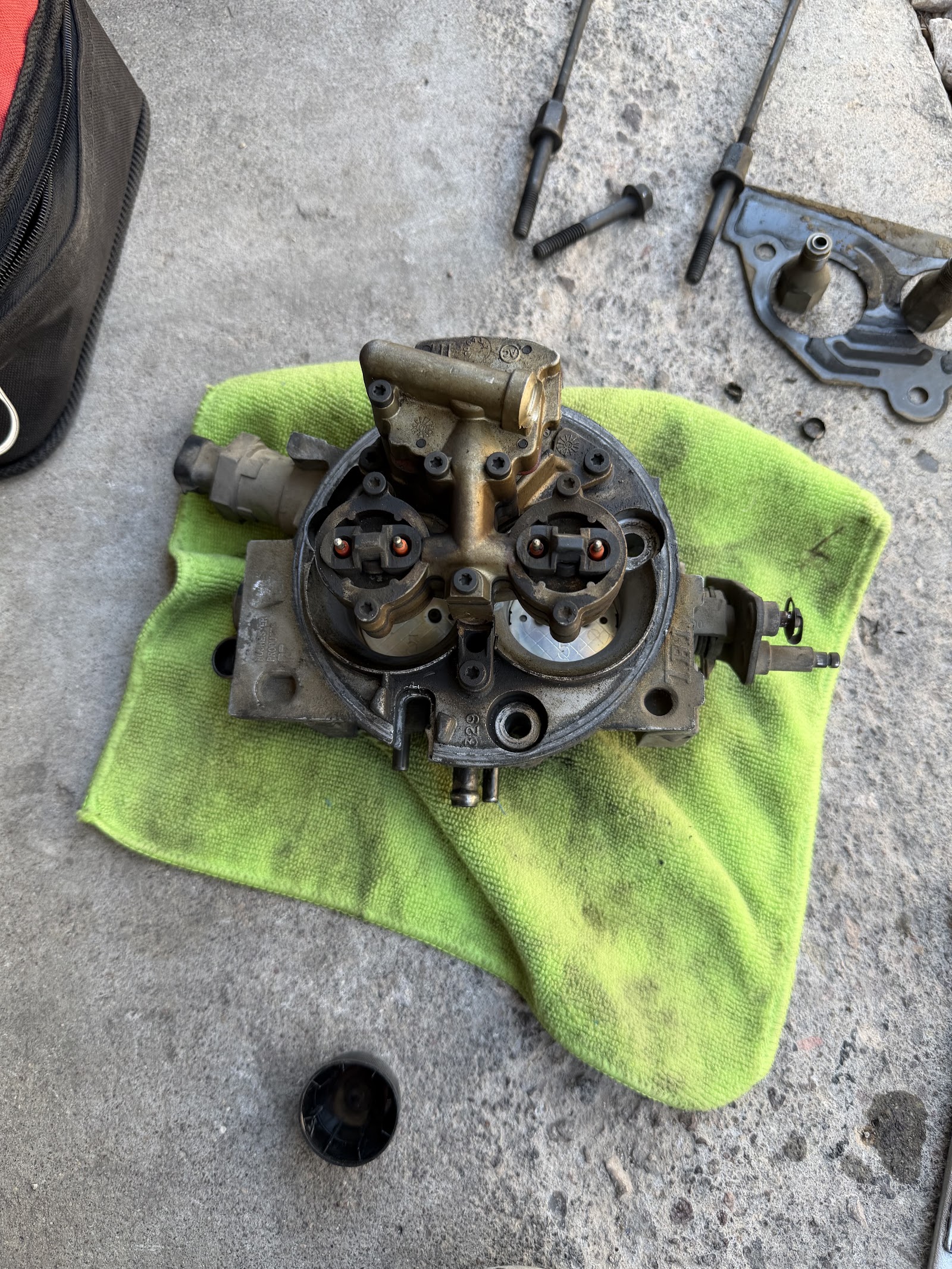 Throttle body injector unit on green towel with tools on concrete
