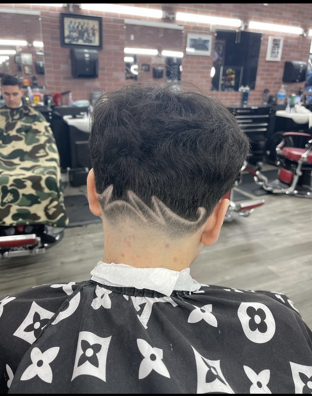 Back view of a textured haircut with an artistic hair design shaved into the nape